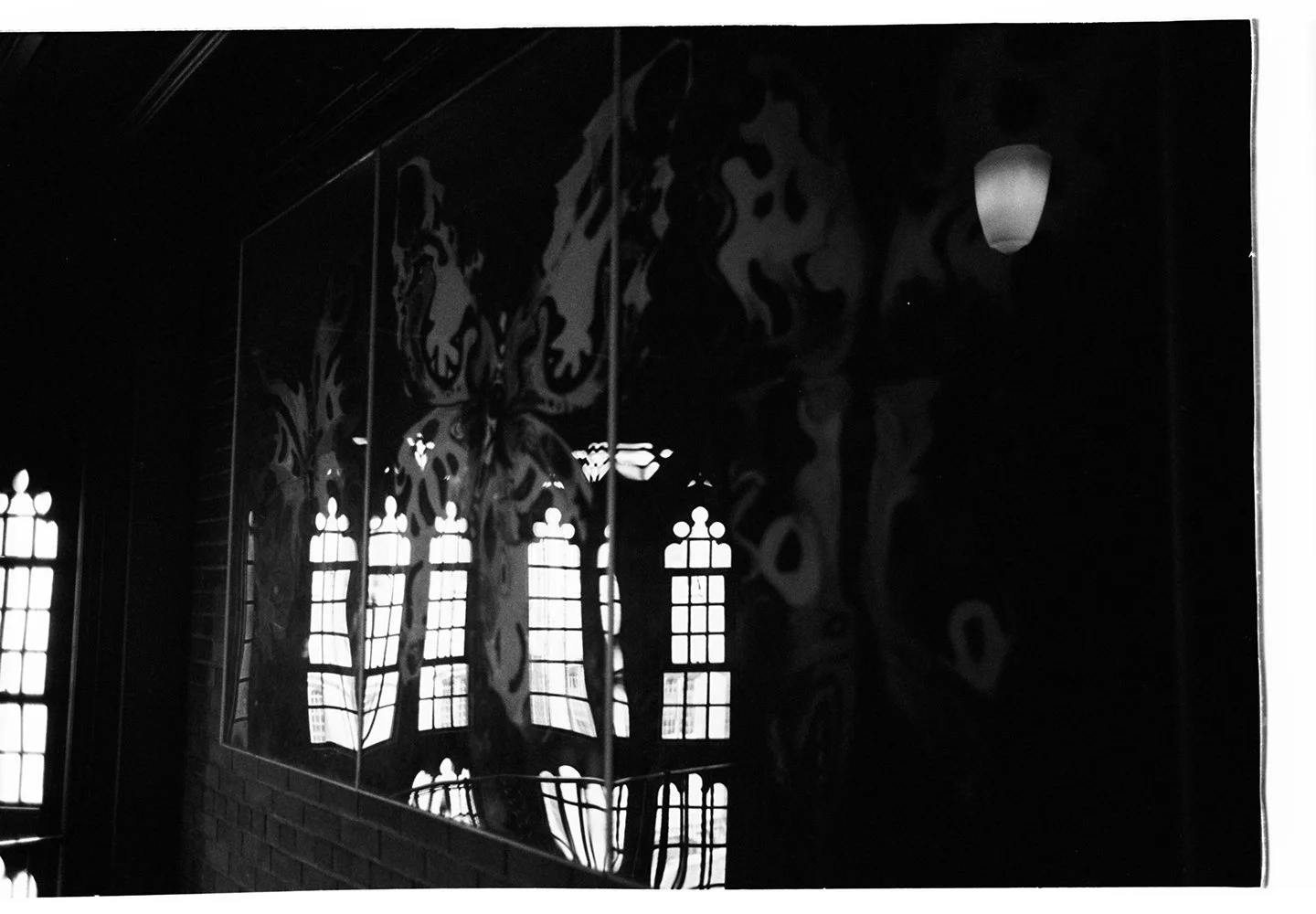Reflection of windows with stained glass and decorative patterns on a shiny black surface.