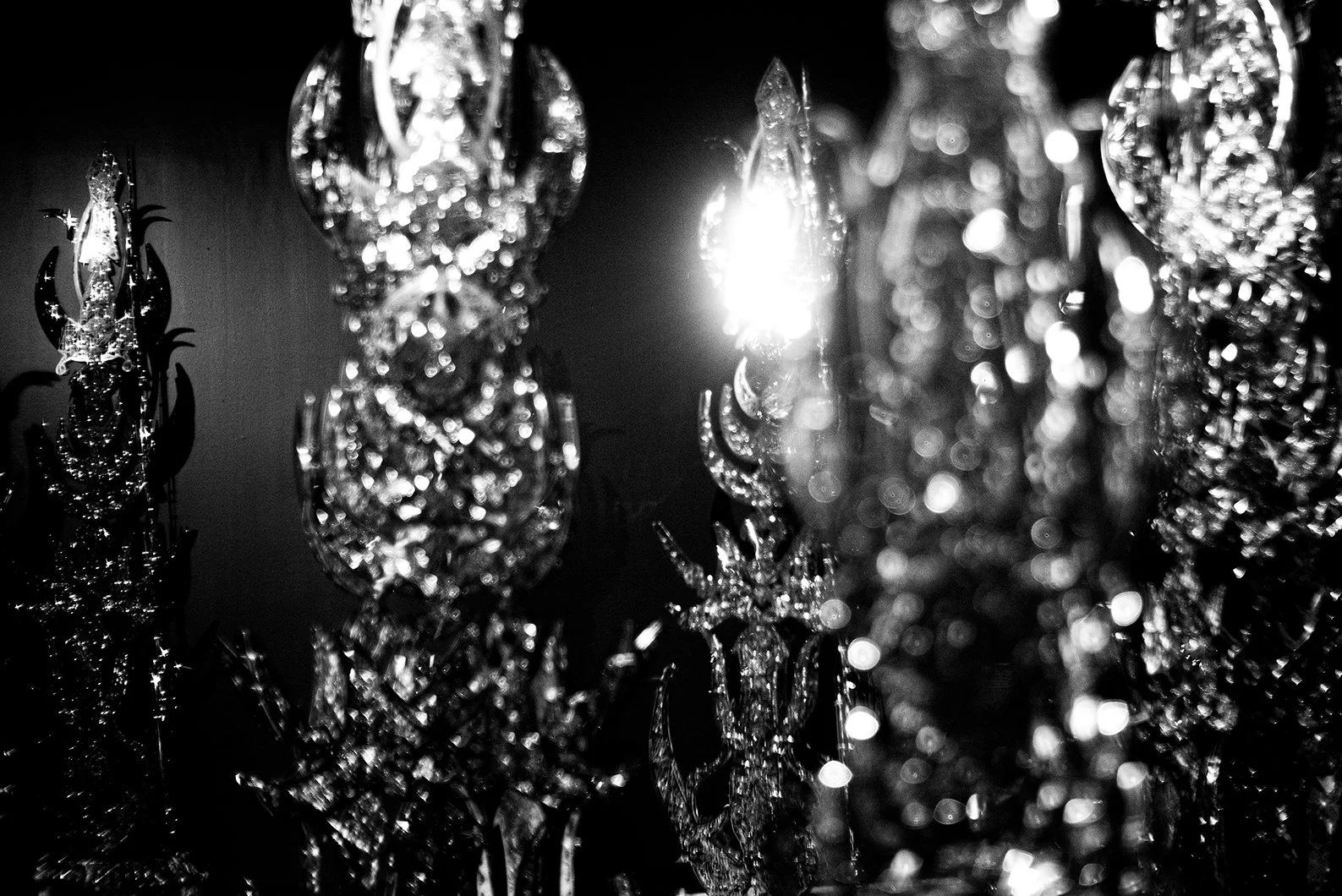 Close-up black and white photo of crystal chandelier with light shining through.