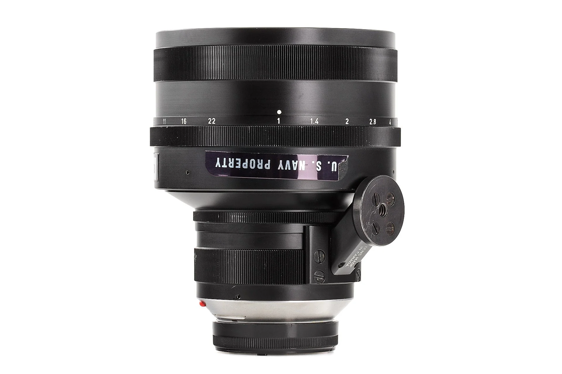 Close-up of a black camera lens, with white measurement markings, mounted on a black tripod mount, isolated on a white background.