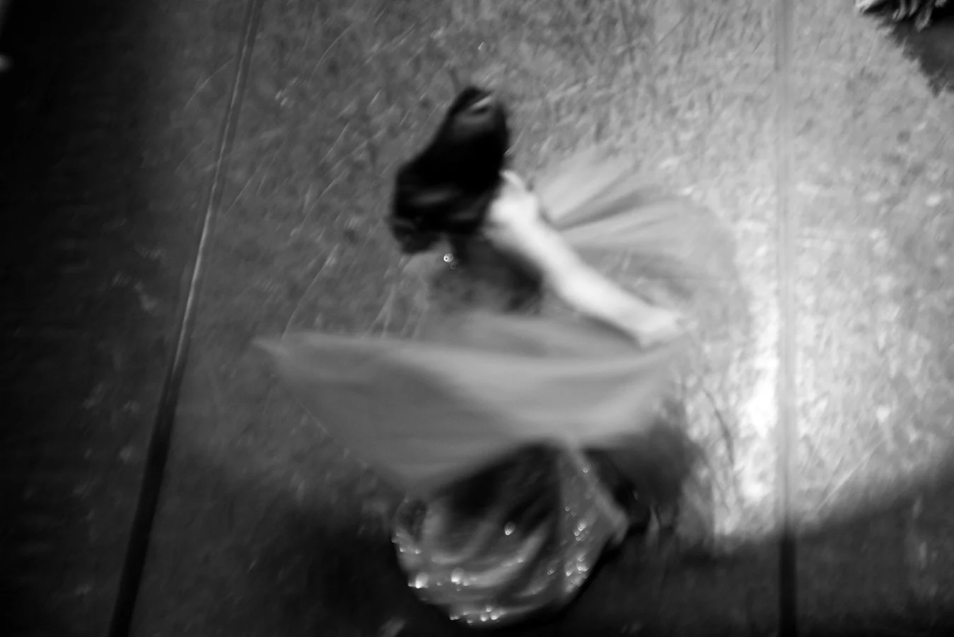 A black and white photo of a shopping bag with a bouquet of flowers inside on a tiled floor.