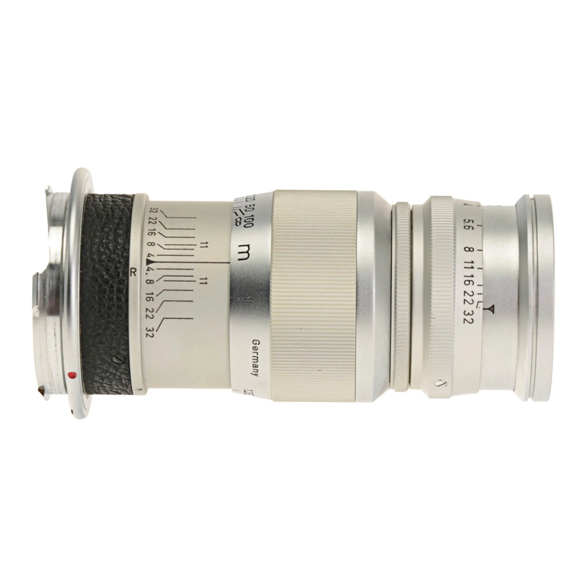 A vintage camera lens with a silver body, black textured grip, and various markings and measurements in meters and feet.