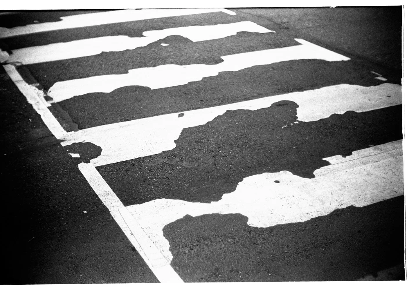 Black and white photograph of a damaged pedestrian crosswalk on a street