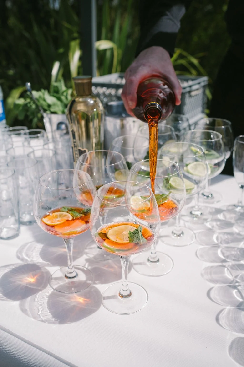 Orange wedding cocktails on a white tablecloth outside.