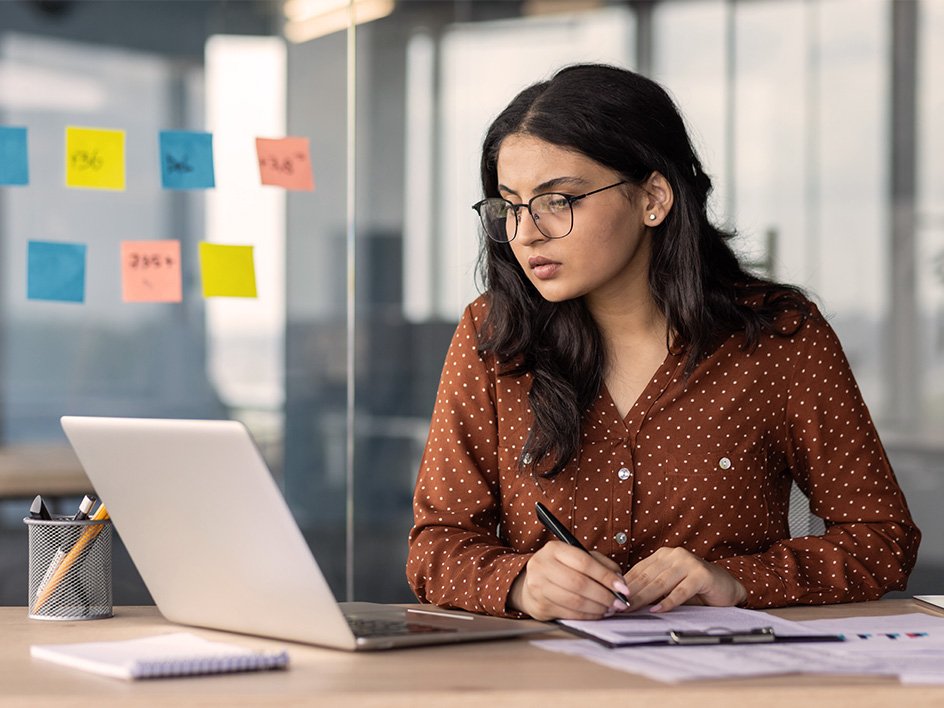 Photograph of a woman working on her laptop, doing a free company scan to gain actionable insights to improve workplace health, boost morale, and create a burnout-resistant culture.
