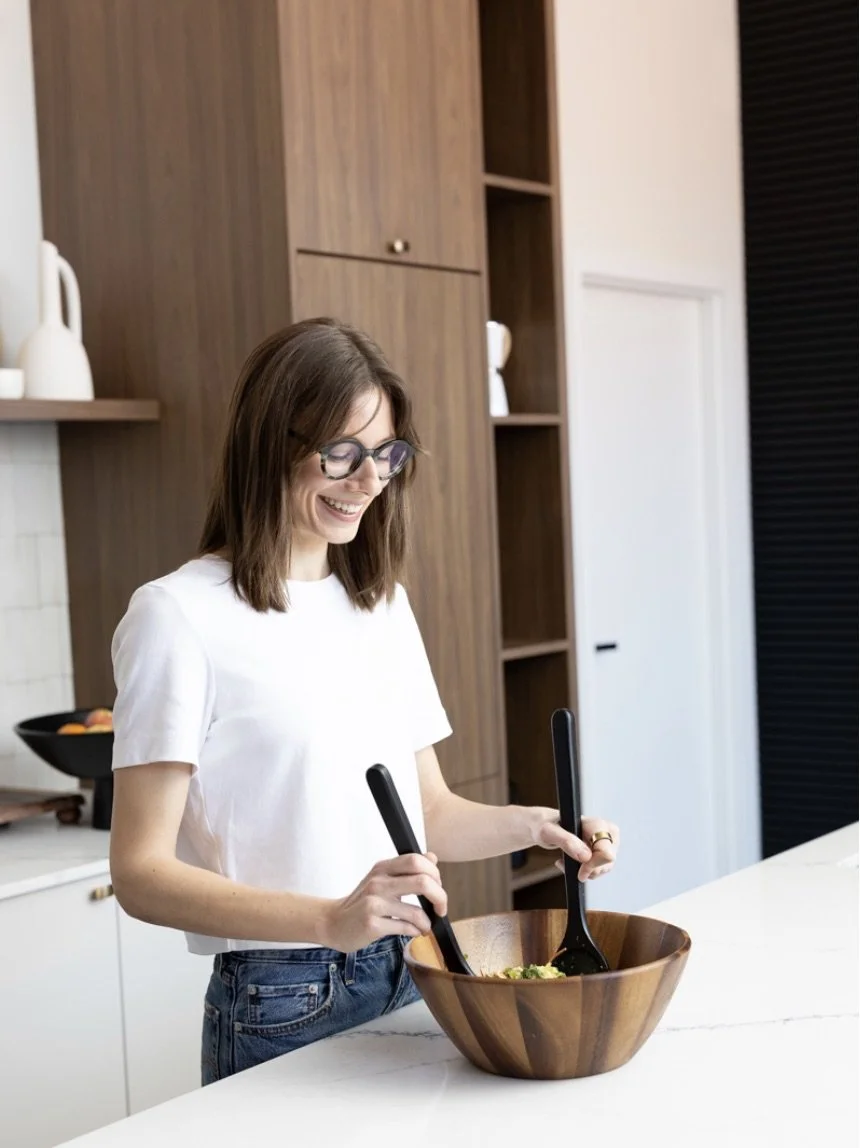 Emilia tossing salad in kitchen