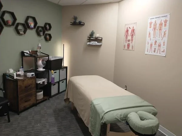 Massage therapy treatment room with cushioned table, anatomical posters, shelves, and storage cabinets