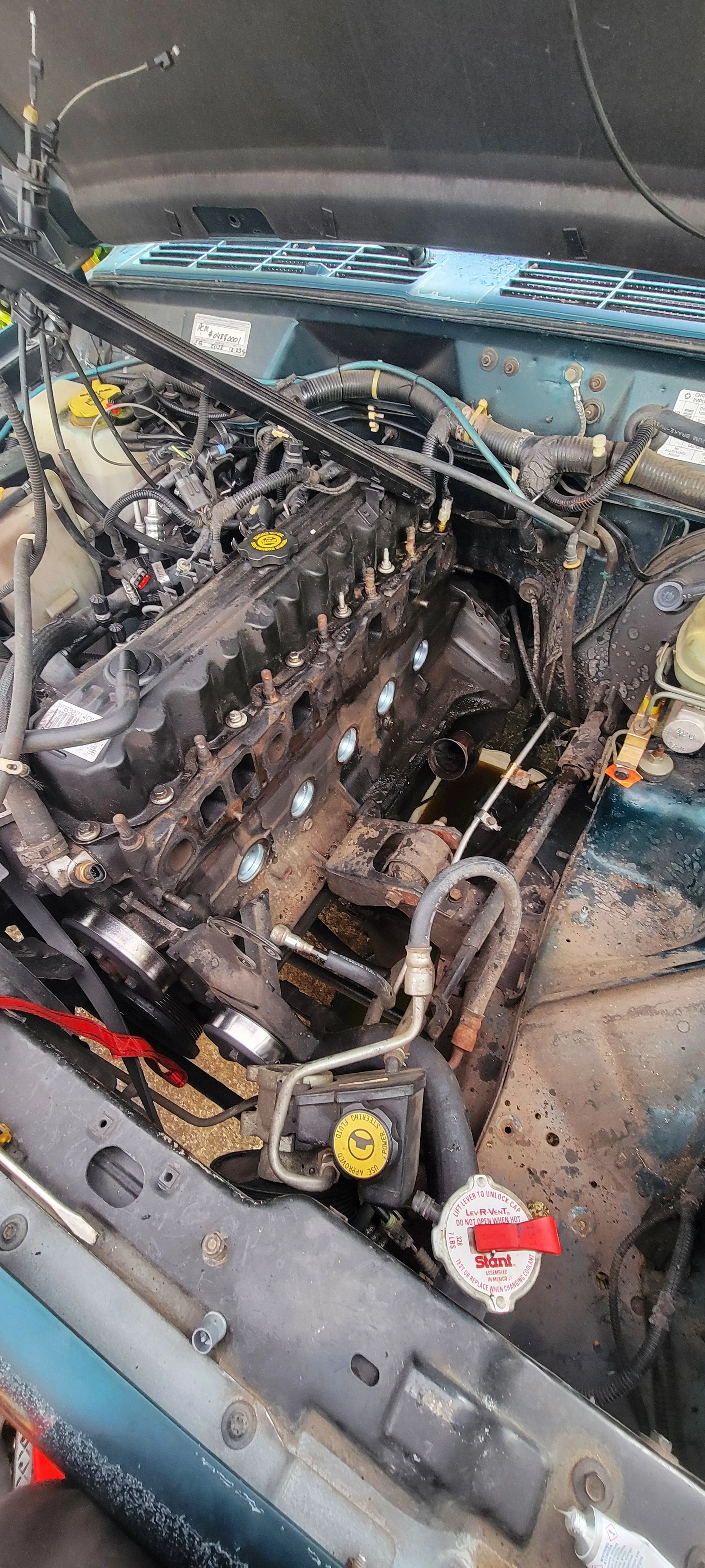 View of a car engine with the cylinder head removed, exposing the engine block and various mechanical components.