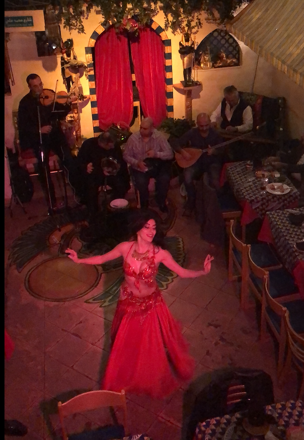 Tania is mid-spin during a dance performance and surrounded by a live band playing the music.