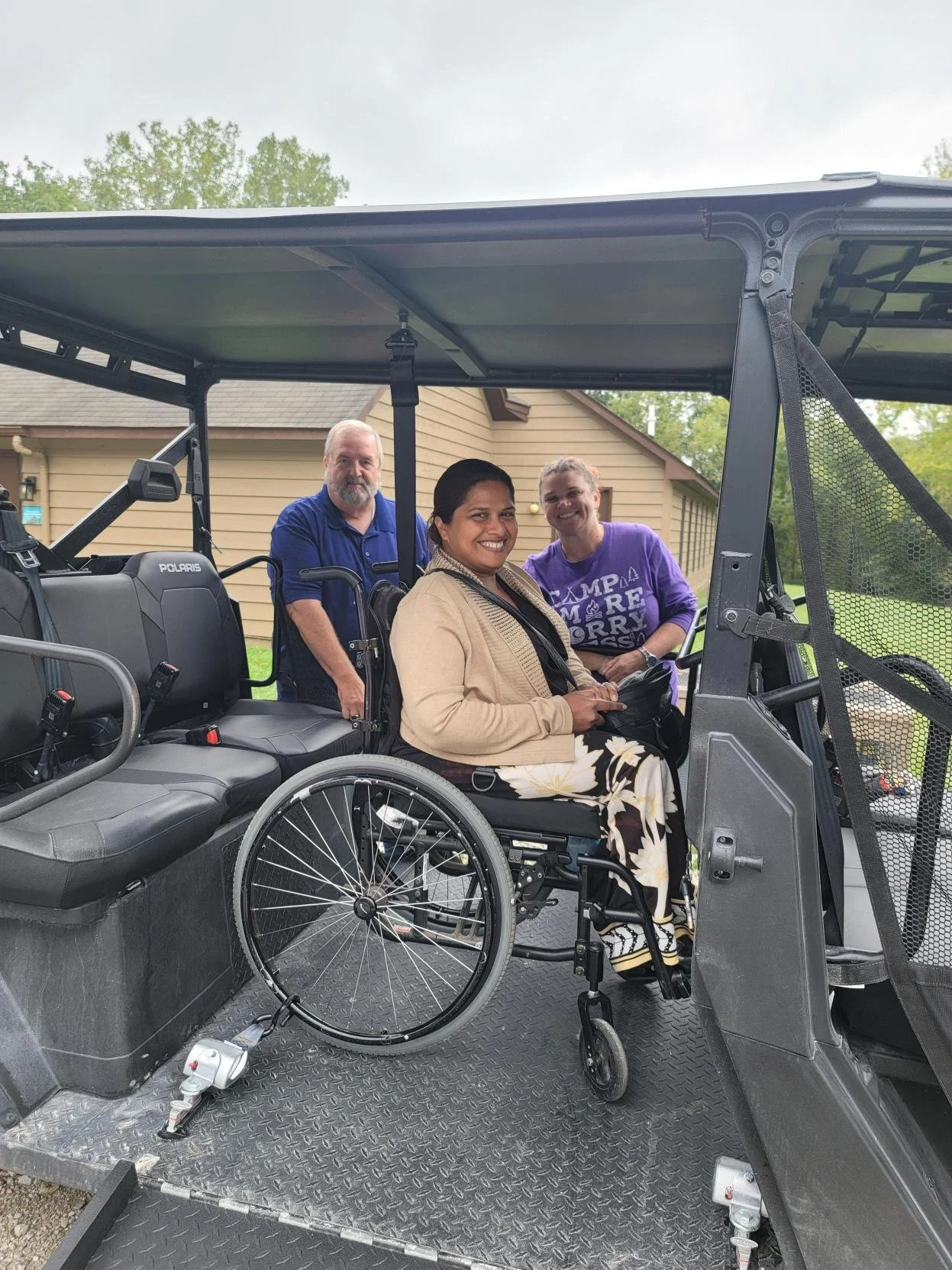 Three people, including one person in a wheelchair on a Polaris ATV