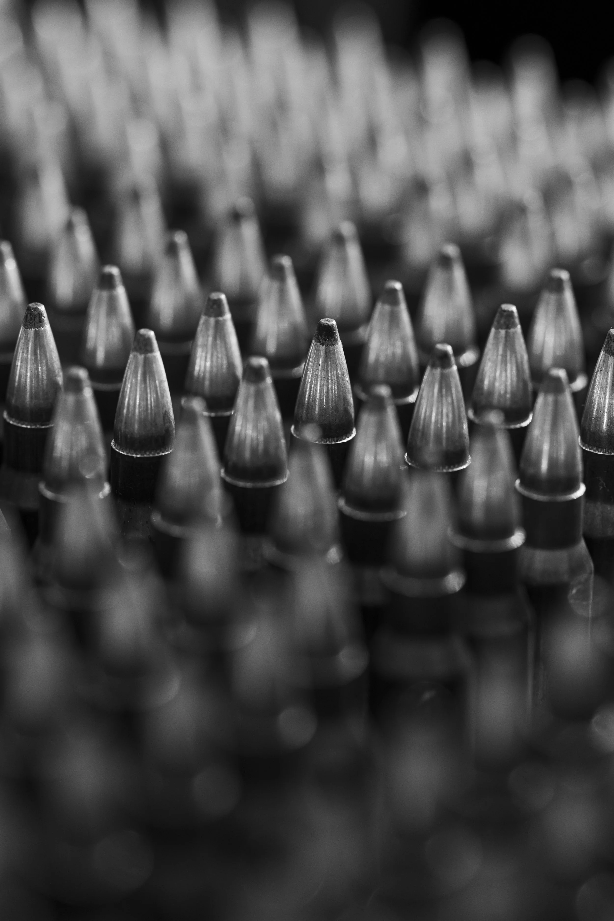 Close-up of numerous metallic bullets arranged in rows, captured in black and white.