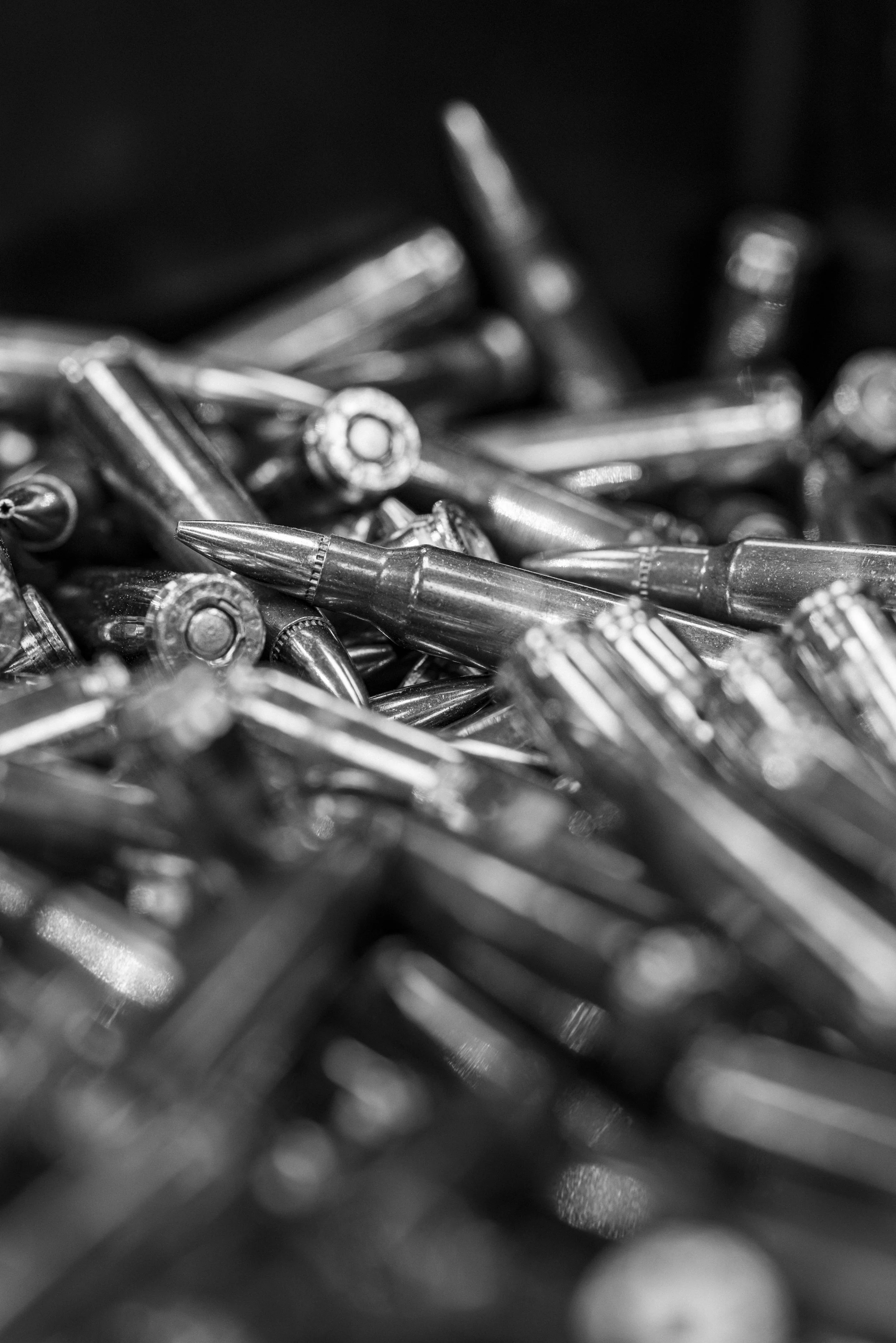 Close-up of metallic bullets and ammunition in black and white.