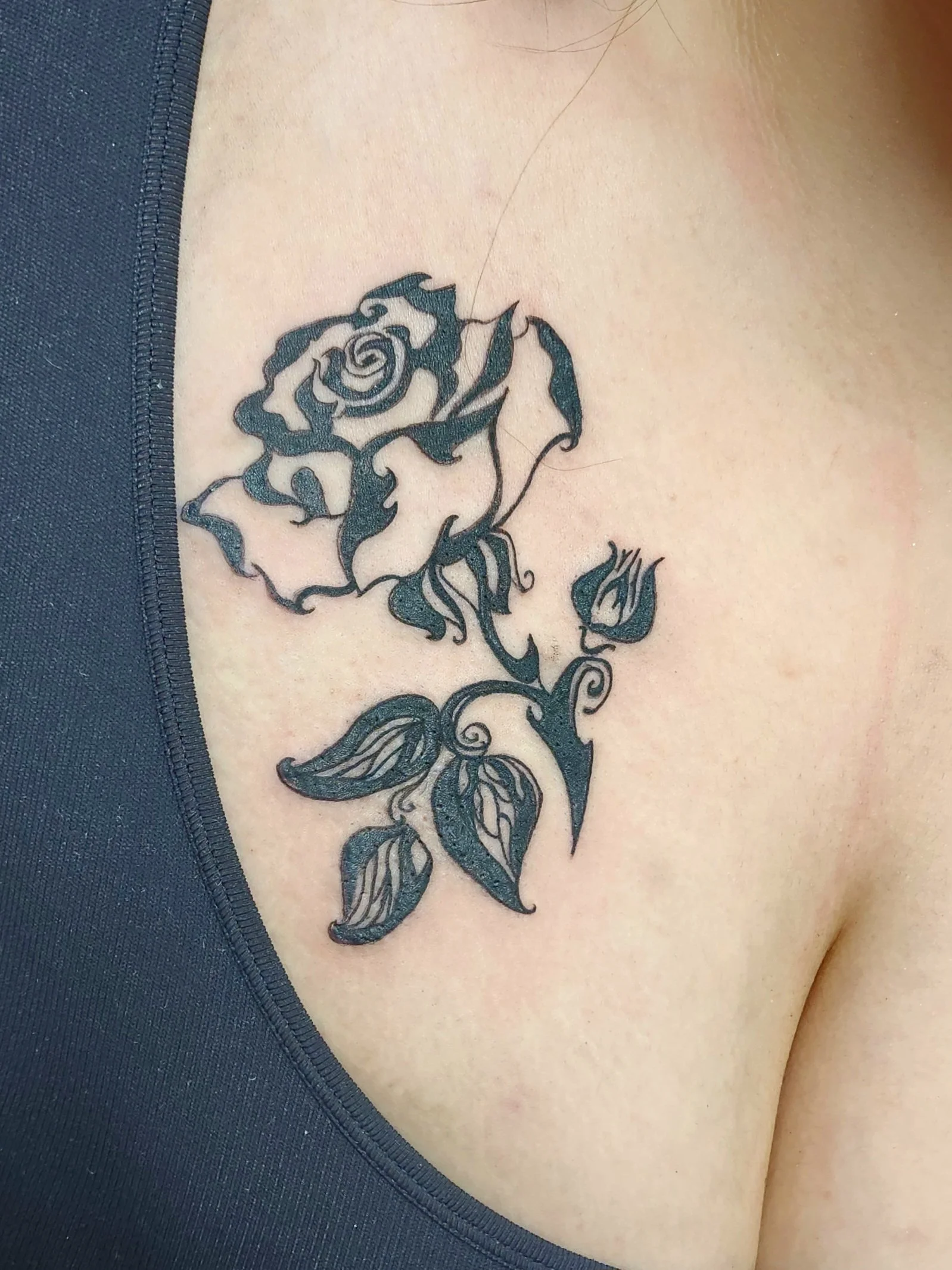 Tattoo of a rose with stem and leaves including a small rose bud off to the side