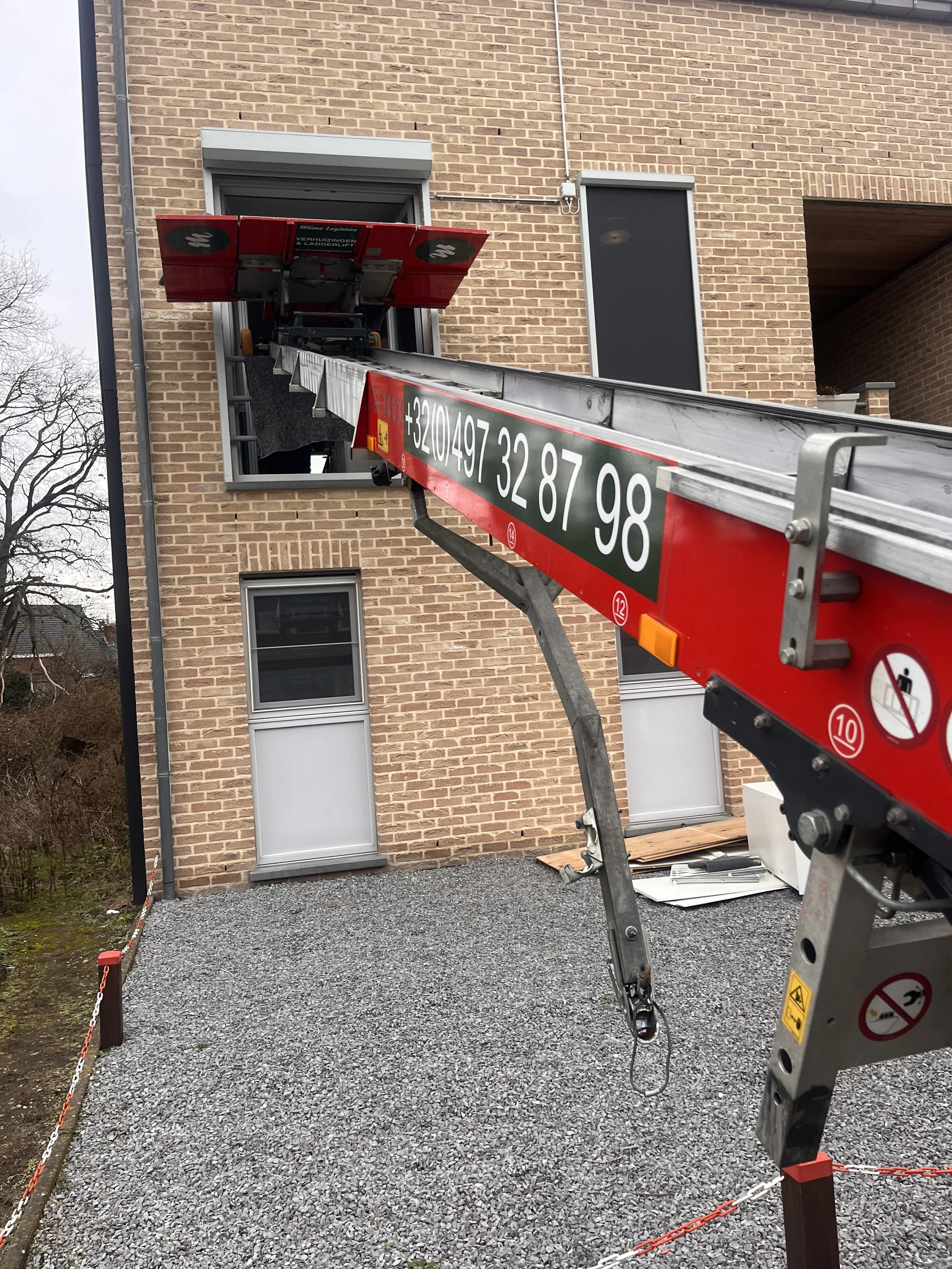 Ladder voor het reinigen of het uitvoeren van werkzaamheden aan een raam van een gebouw met een bakstenen gevel.