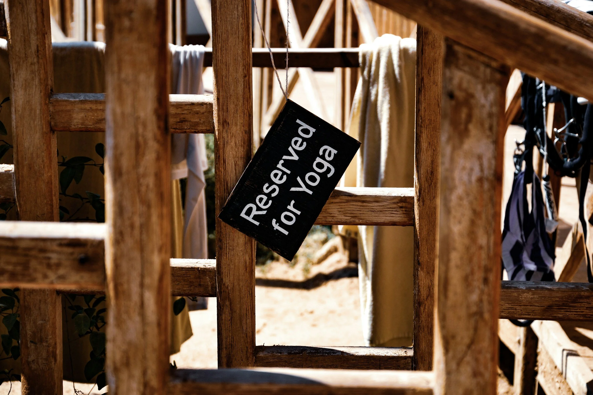 A wooden outdoor structure with clothes hanging on it, containing a sign that reads 'Reserved for Yoga'.