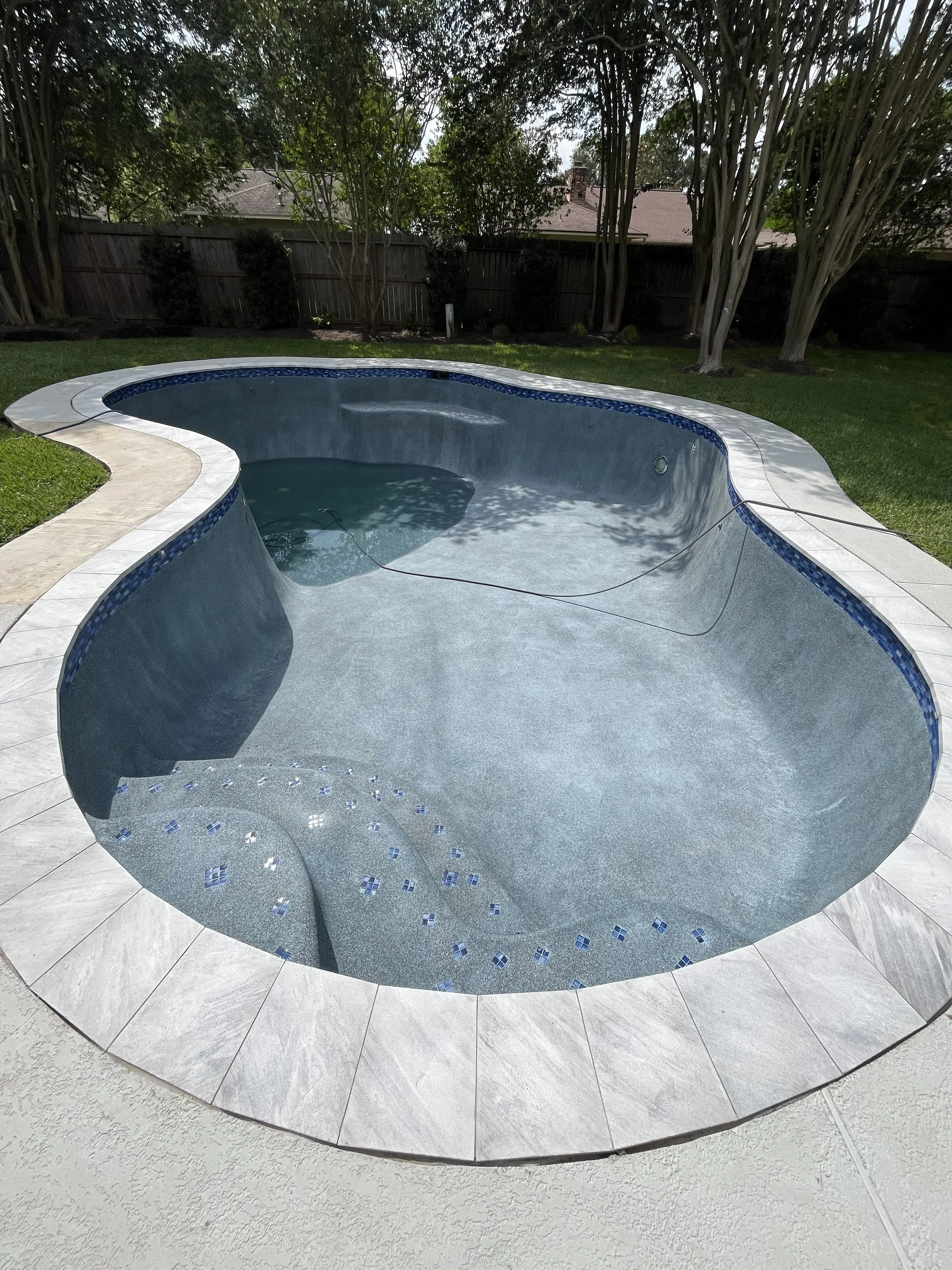 Complete swimming pool renovation in Falcon Ridge in Friendswood featuring Custom mosaic accents, sandblasted marble coping and a StoneScapes Mini Pebble  plaster.