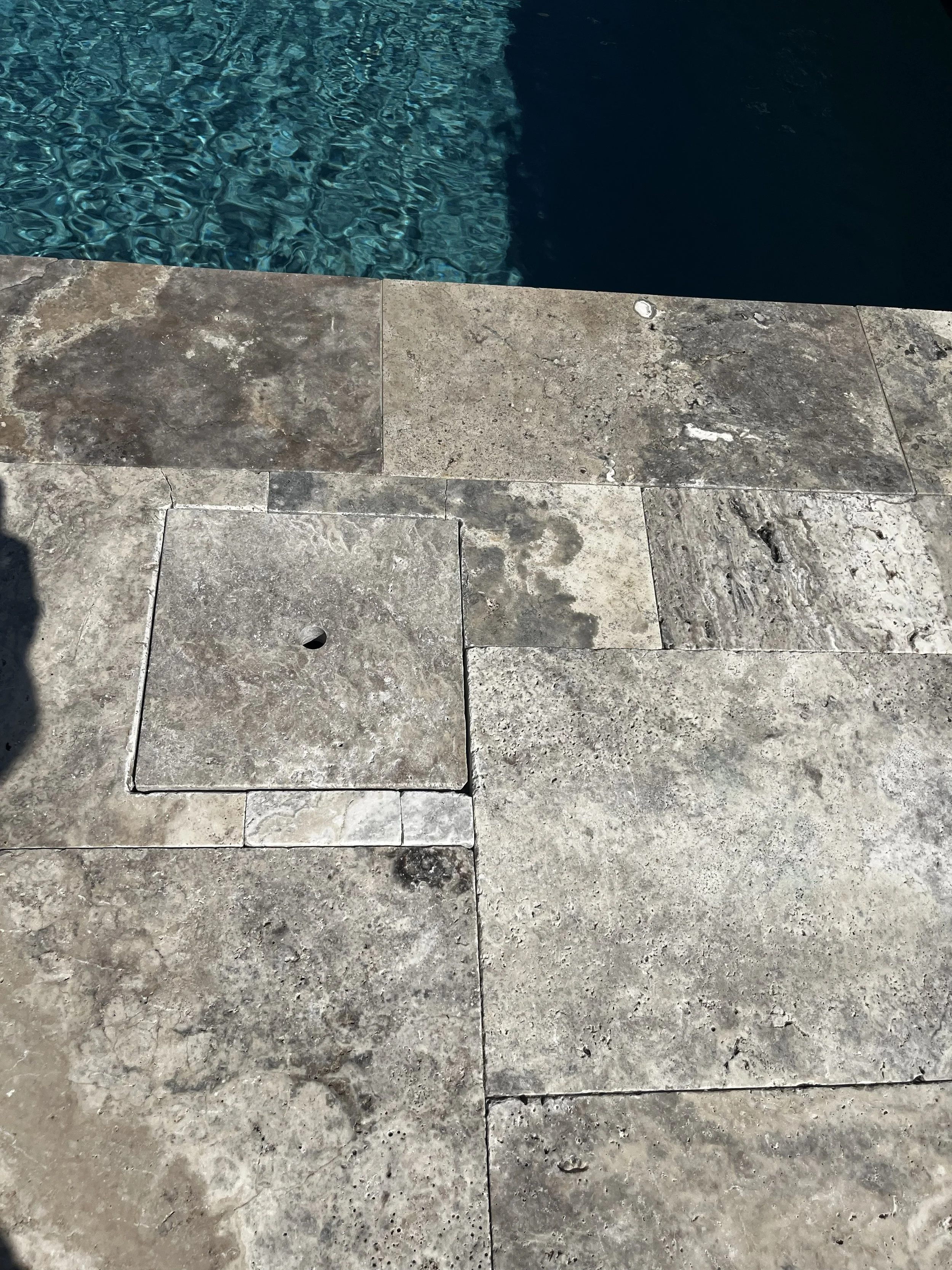 Custom-cut stone skimmer cover fitted into the surrounding pool deck