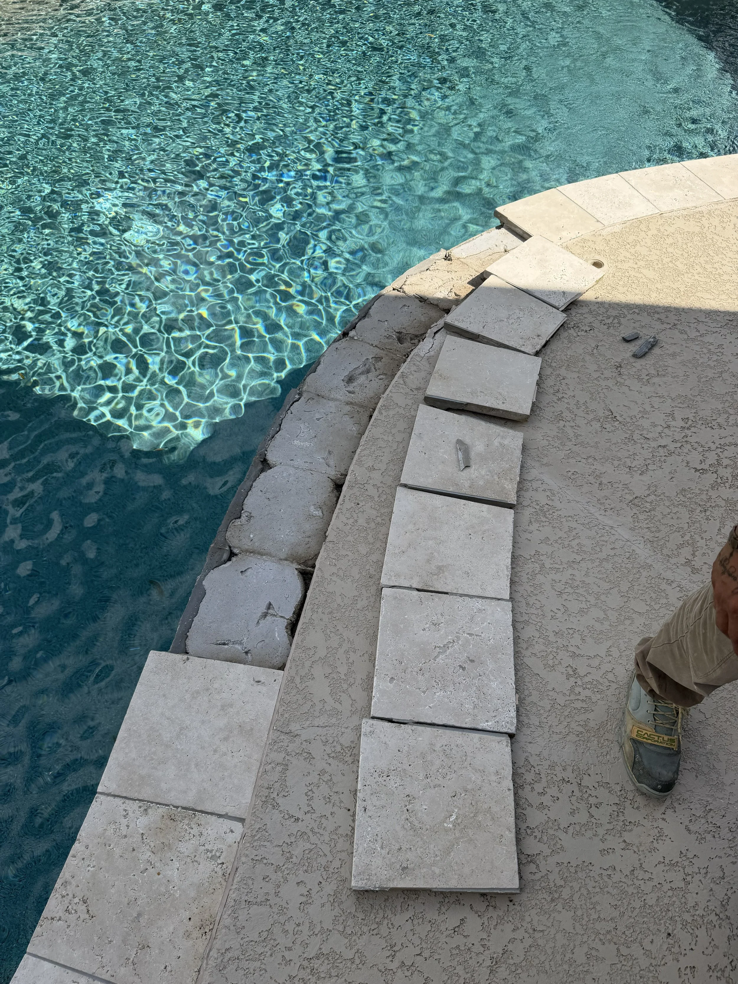 Pool coping stones removed and laid beside the exposed bedding during repair