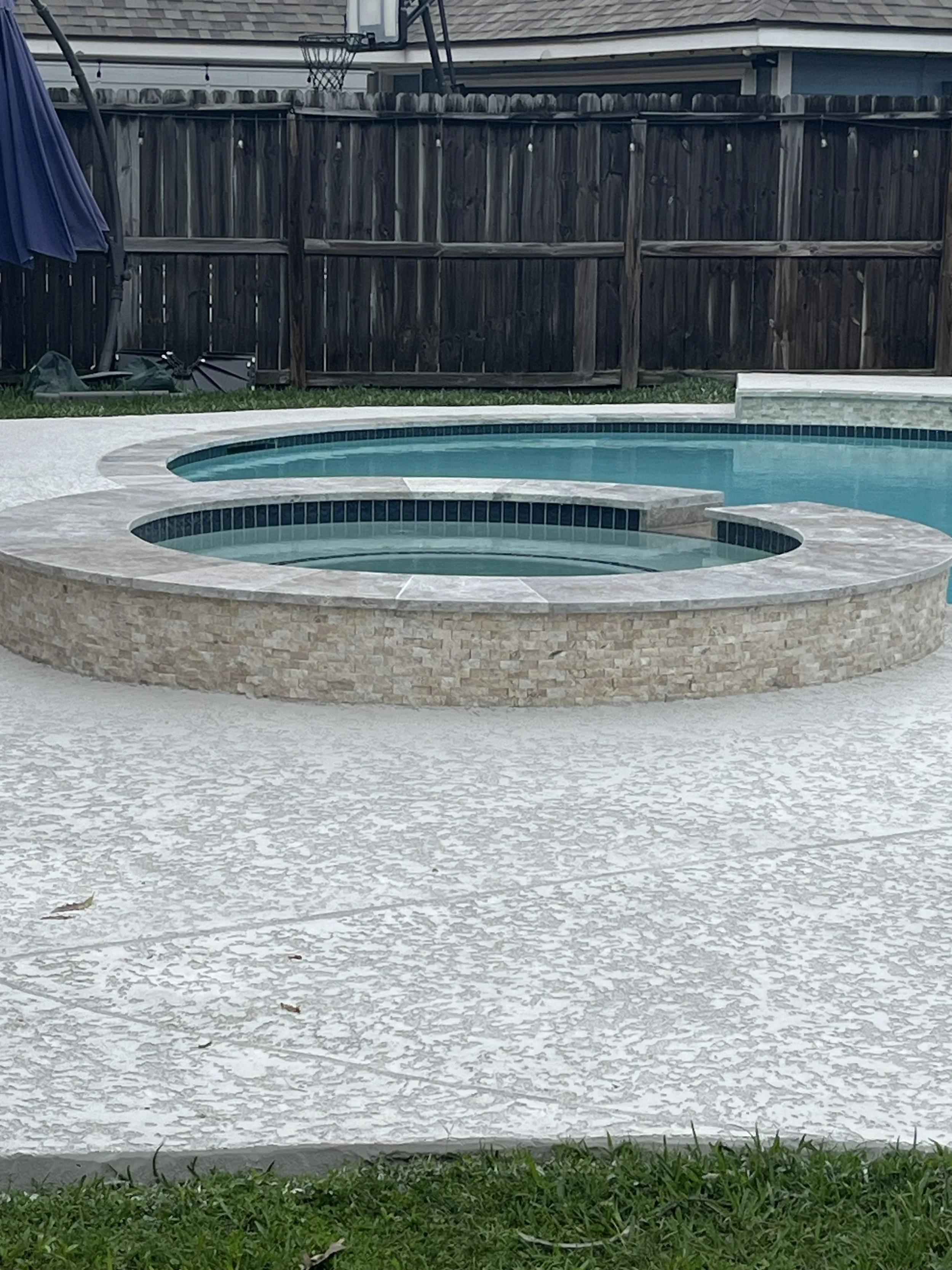 Backyard with an in-ground pool, jacuzzi, green grass, and a wooden fence.