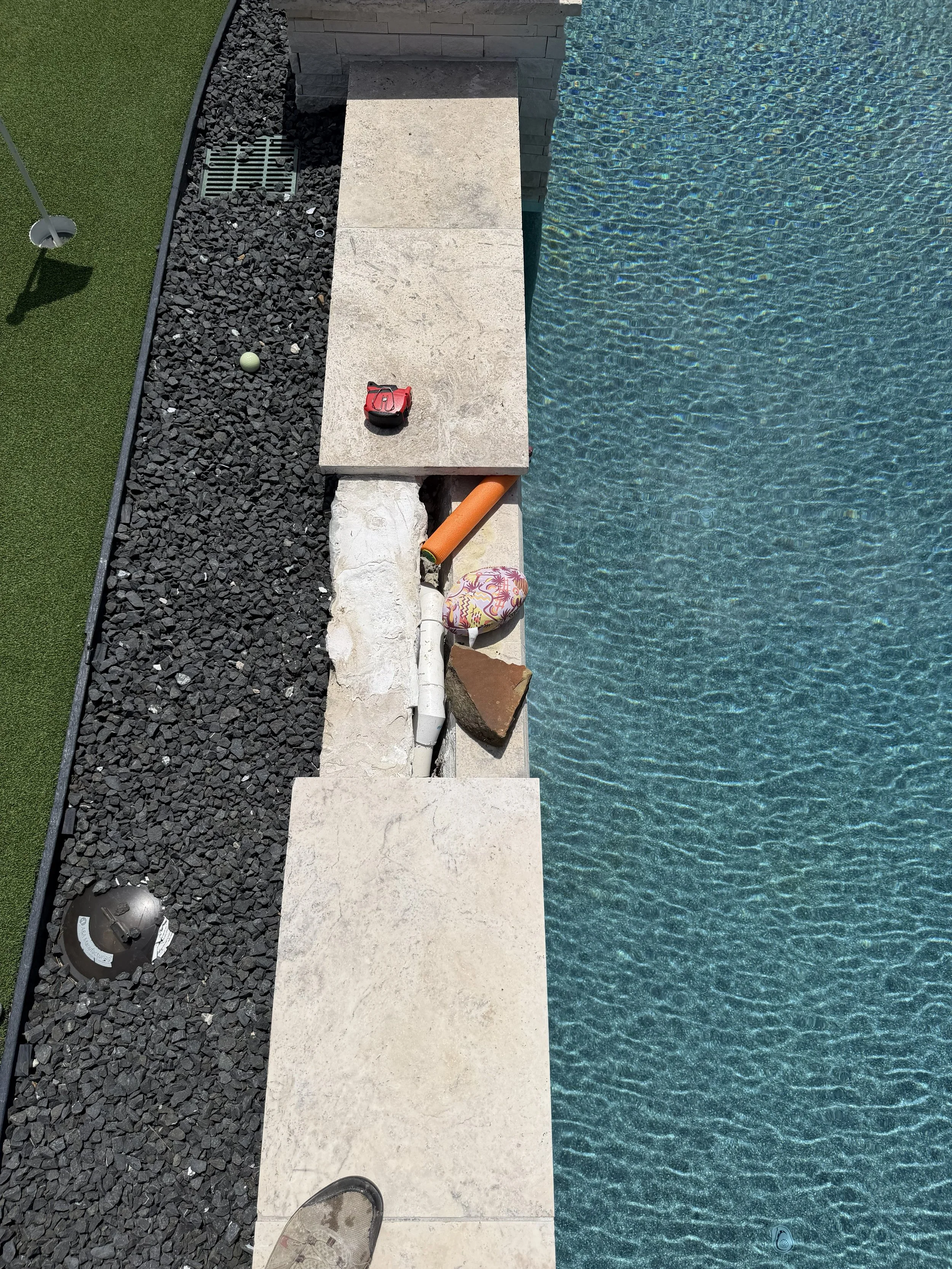Loose pool coping with an exposed opening and makeshift supports beneath the stone