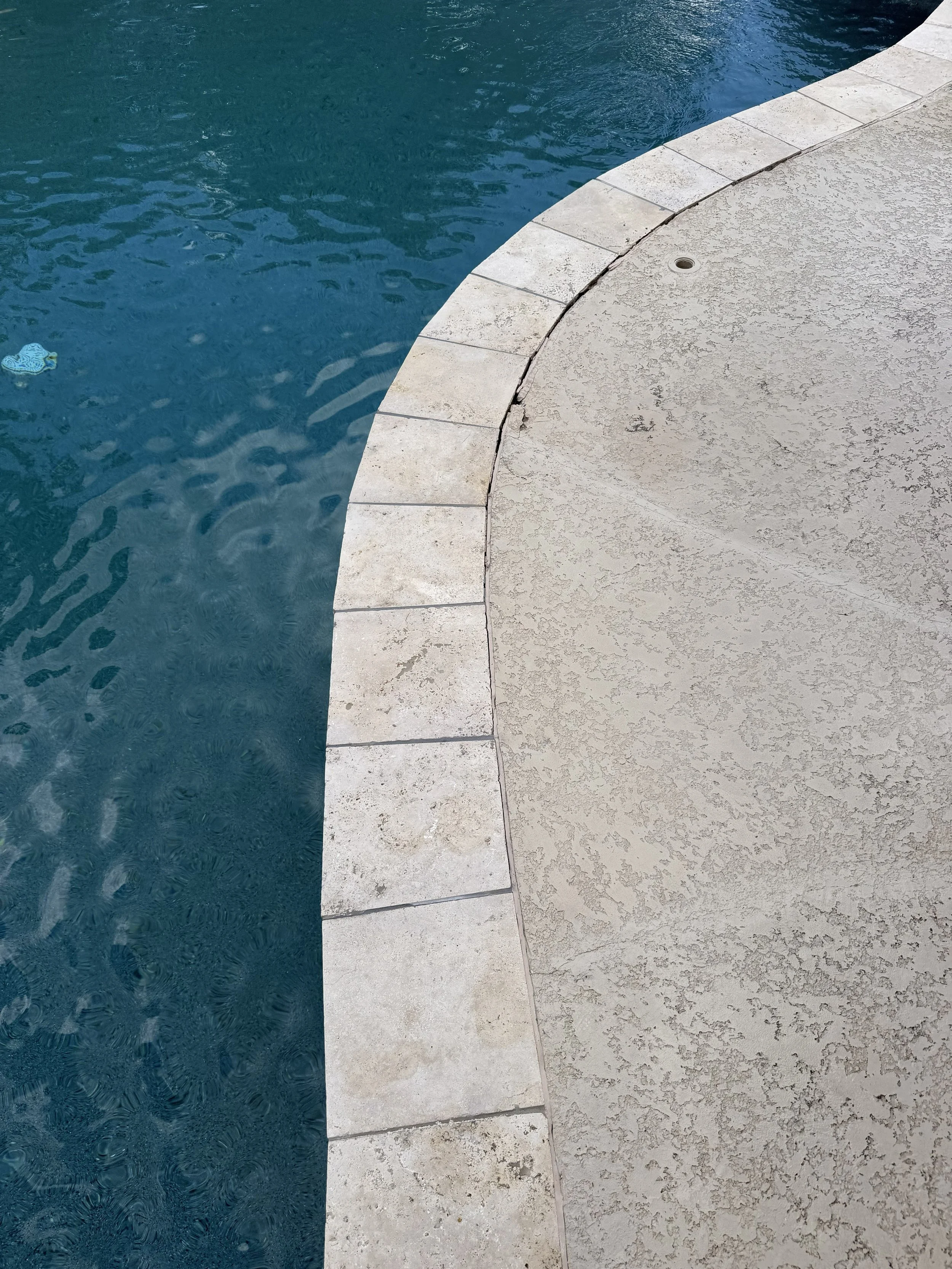 Existing stone coping reinstalled along the curved pool edge