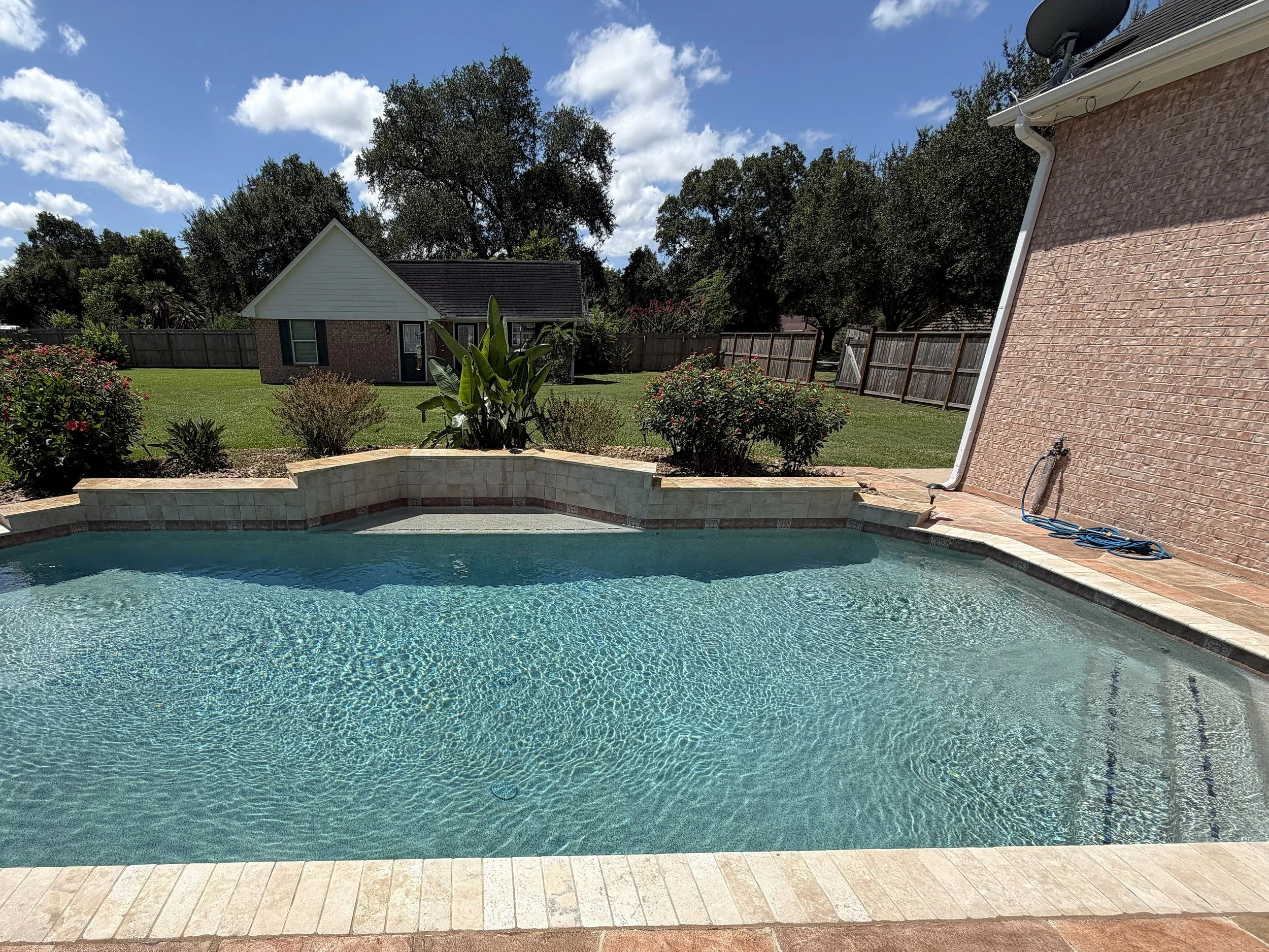 Wide view across the Carrington Oaks pool toward the raised wall and landscaped backyard