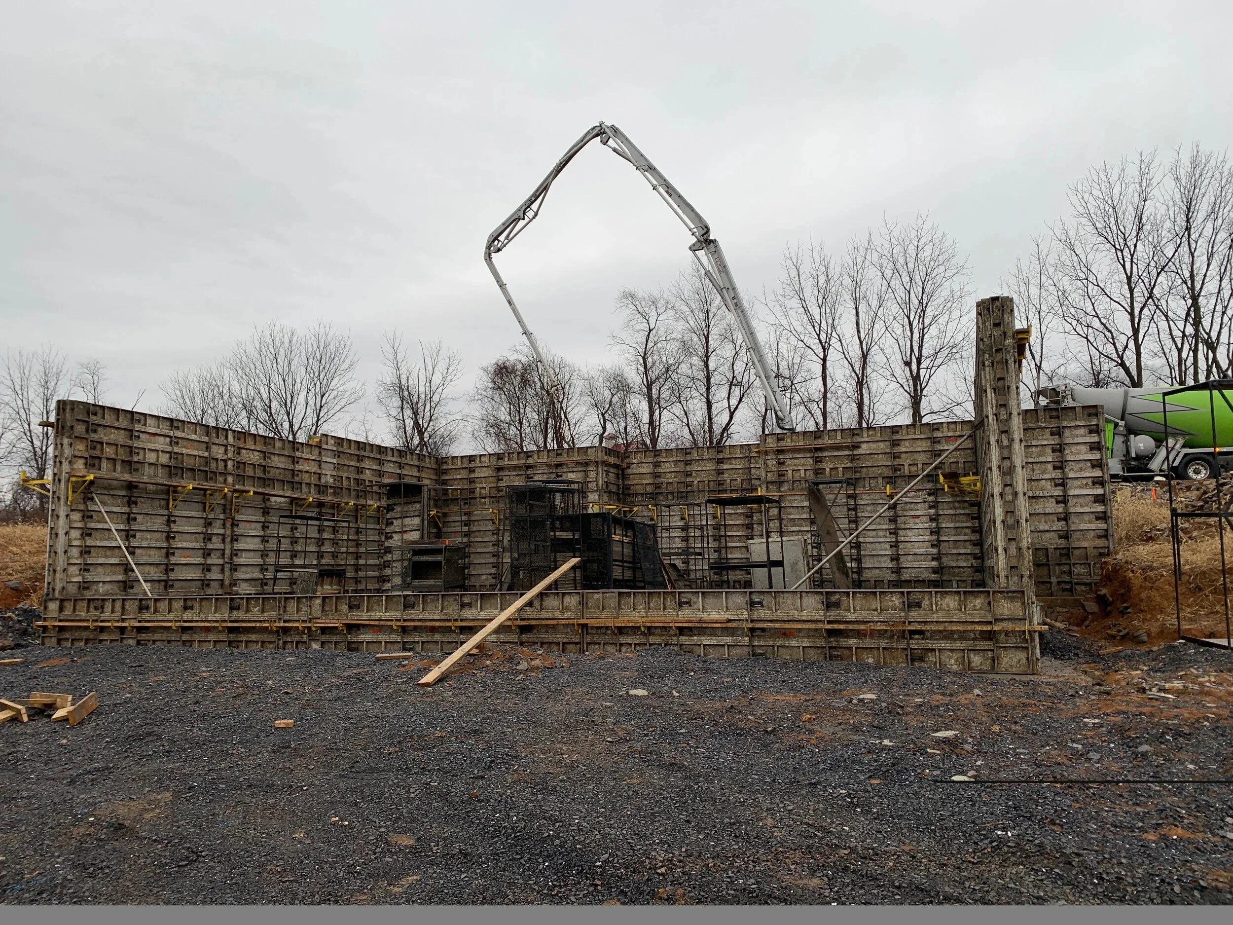 Construction site with wooden formwork for concrete wall and a concrete pump truck with extended arm