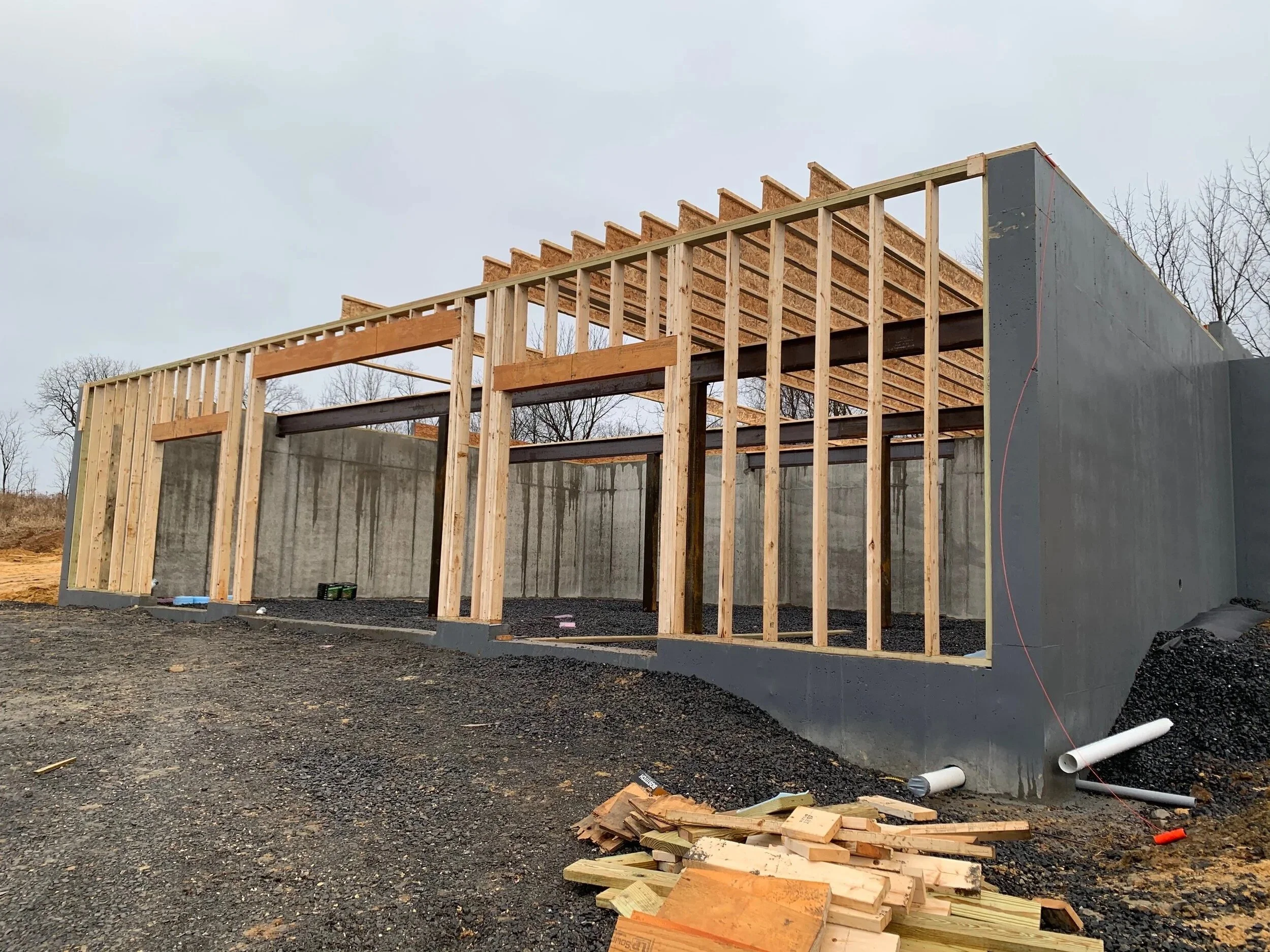 Construction site with wooden framing and concrete walls of a building under construction, overcast sky.
