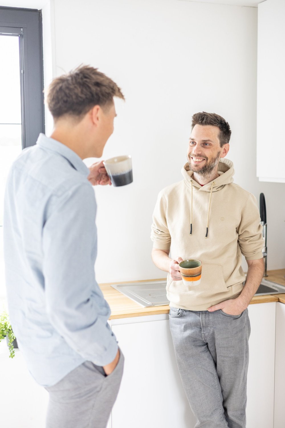 Two colleagues in casual conversation, each holding a coffee mug