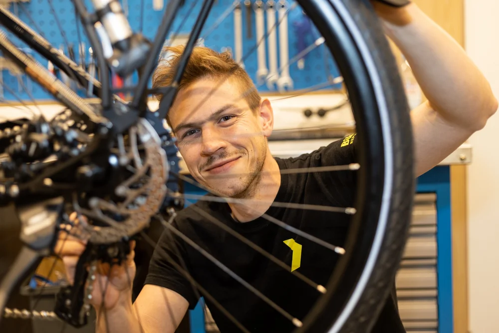 Smiling man working on a bicycle wheel in a repair shop