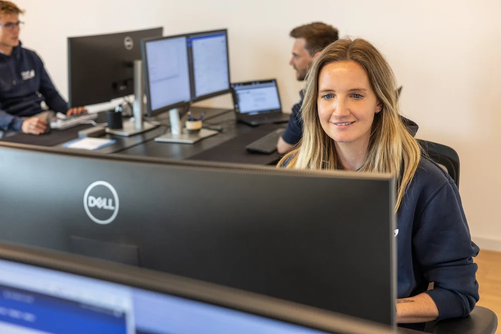 Woman smiling at a multi-monitor workstation with 'Dell' branded screens