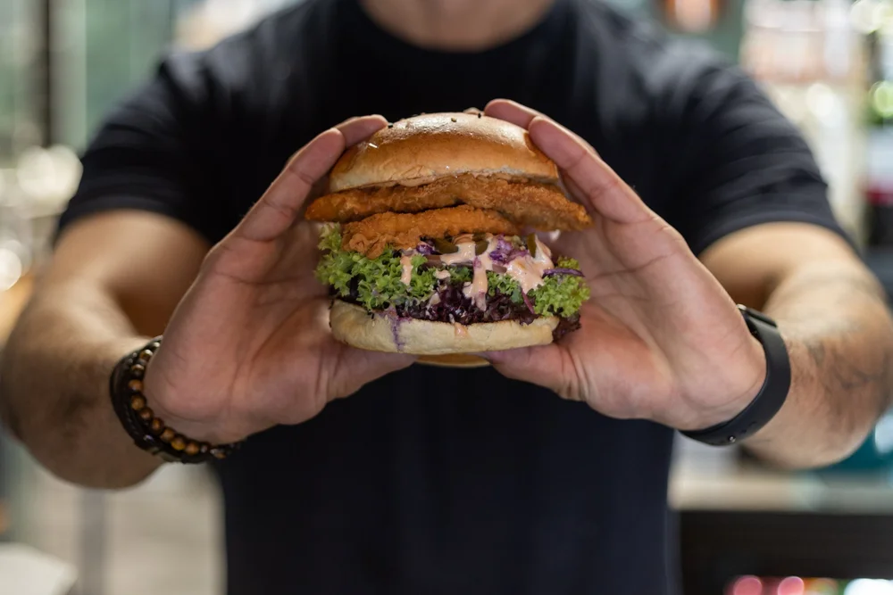 Close-up of hands holding a stacked burger