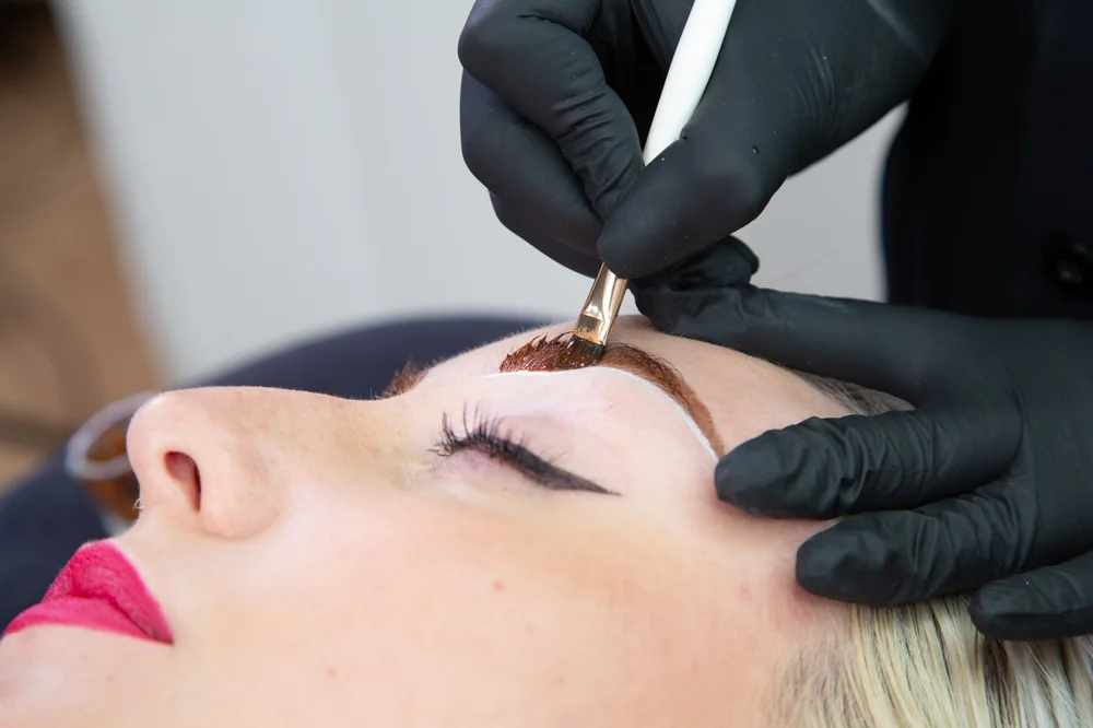 Close-up of an eyebrow microblading procedure, technician's gloved hands working