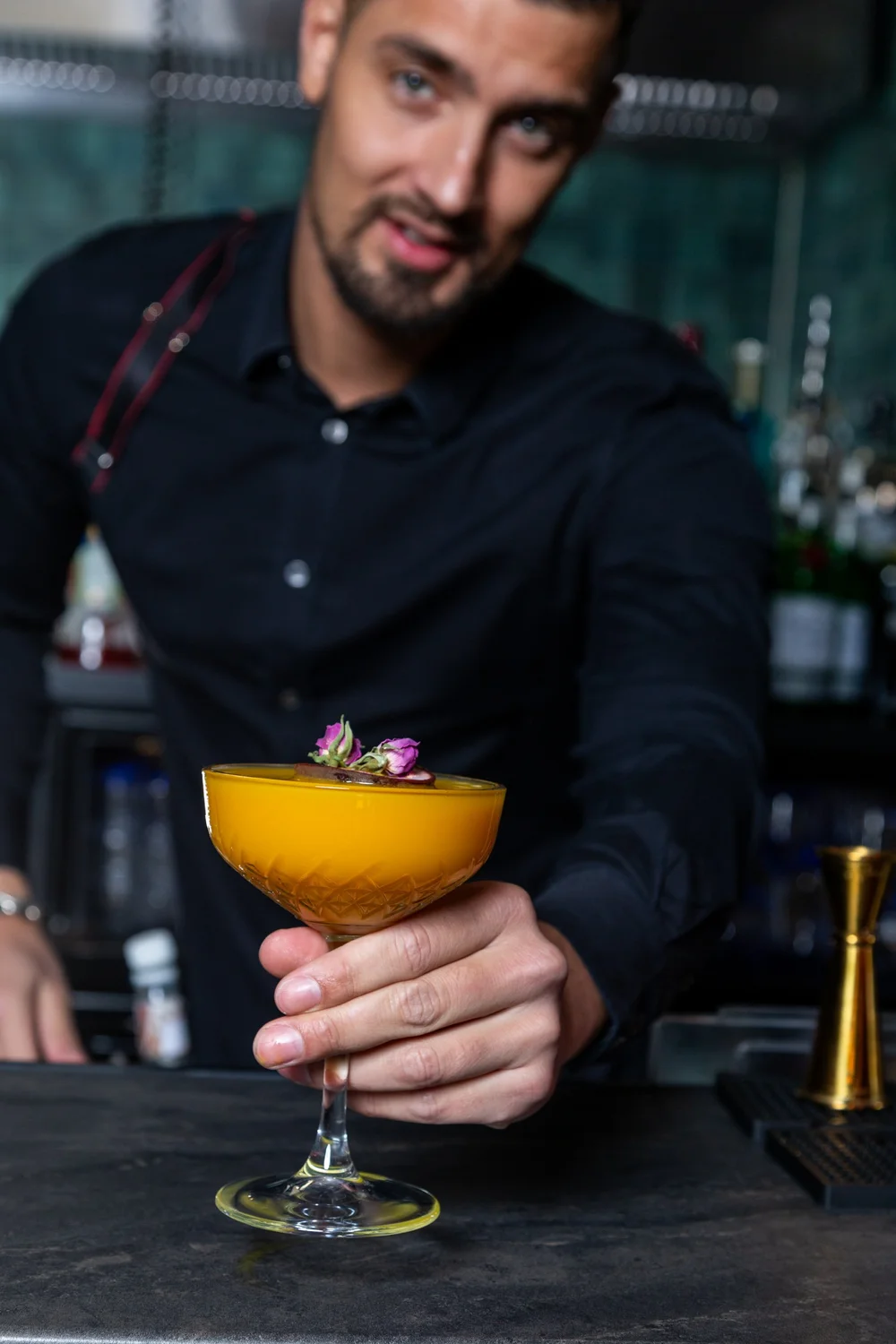 Bartender holding a garnished cocktail in a dark shirt