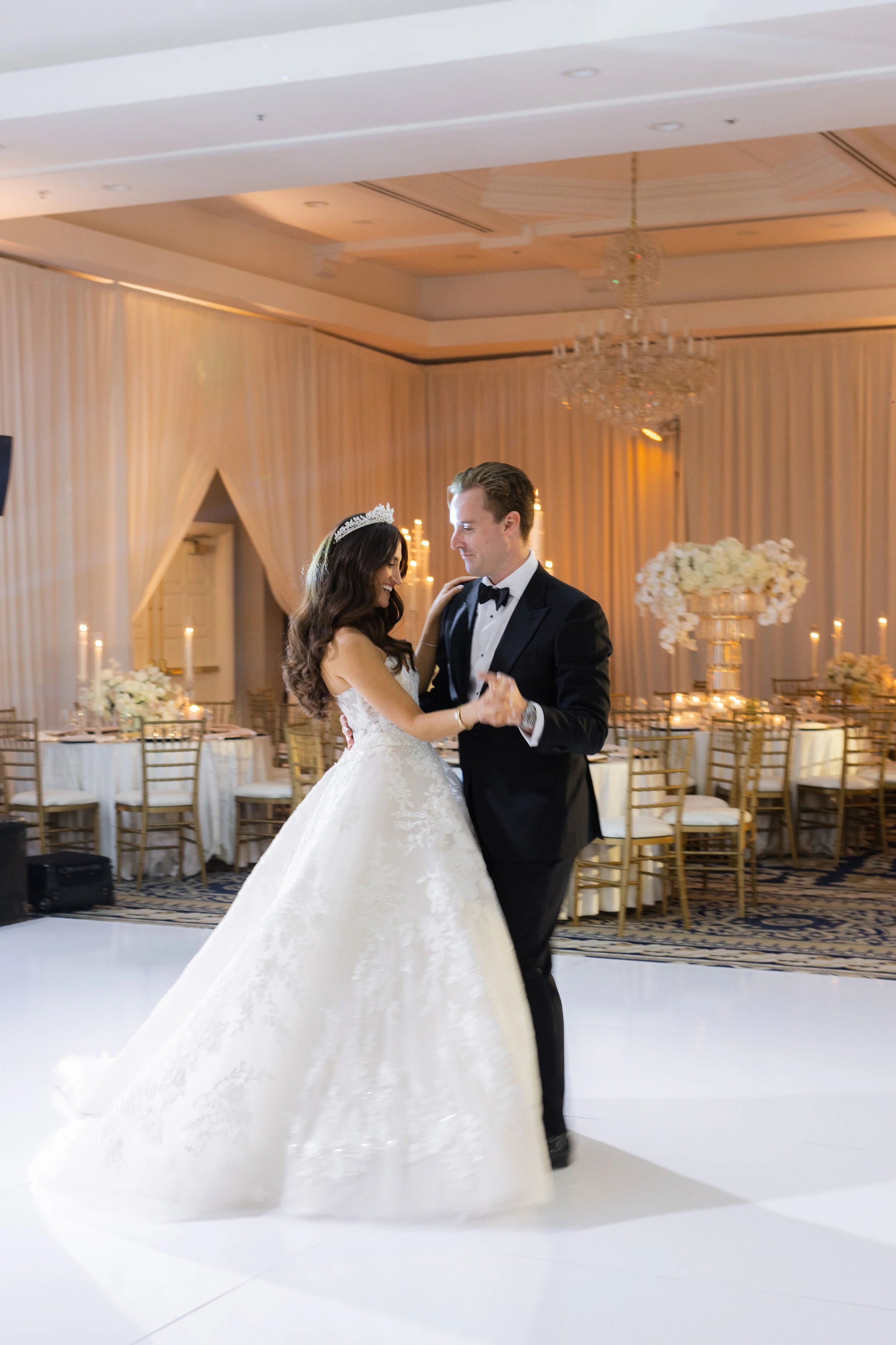 Bride and groom dancing at their wedding reception, surrounded by elegant decorations and candlelight.