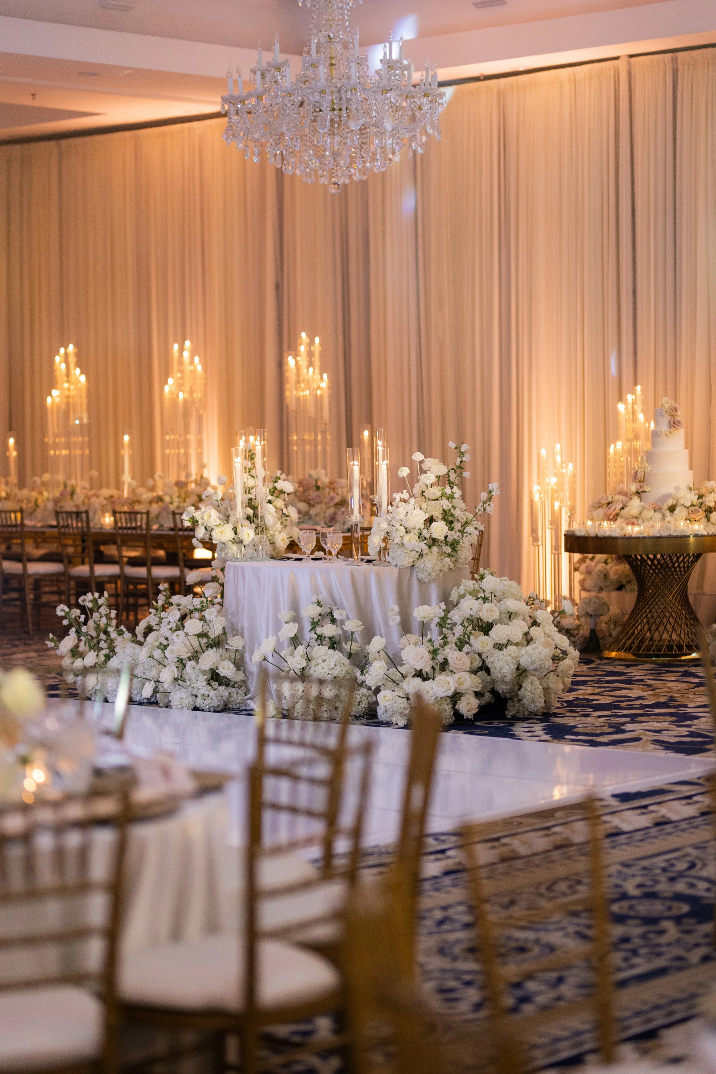 Elegant wedding reception setup with floral arrangements, tall candles, and a chandelier
