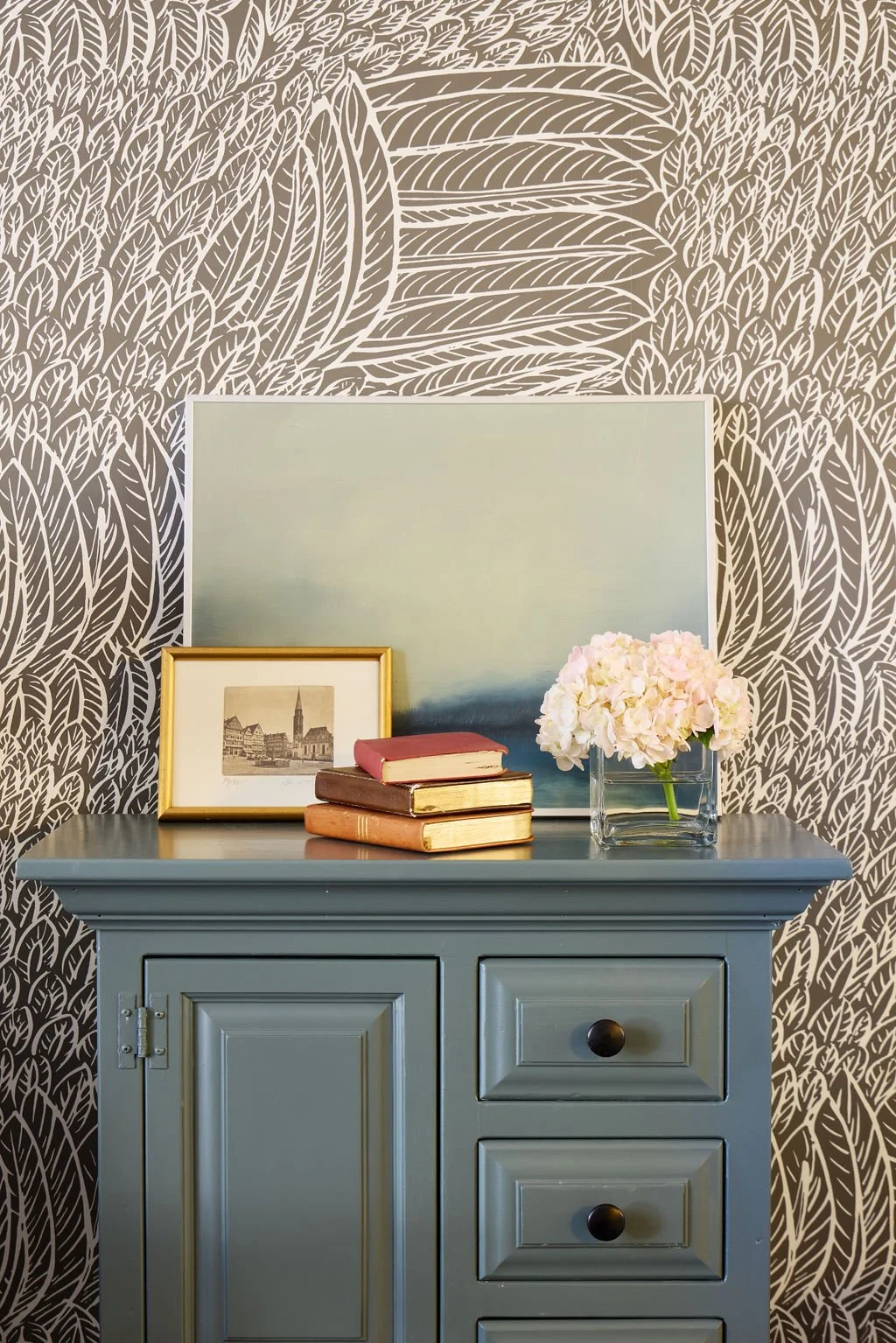 small painted cupboard with art and books