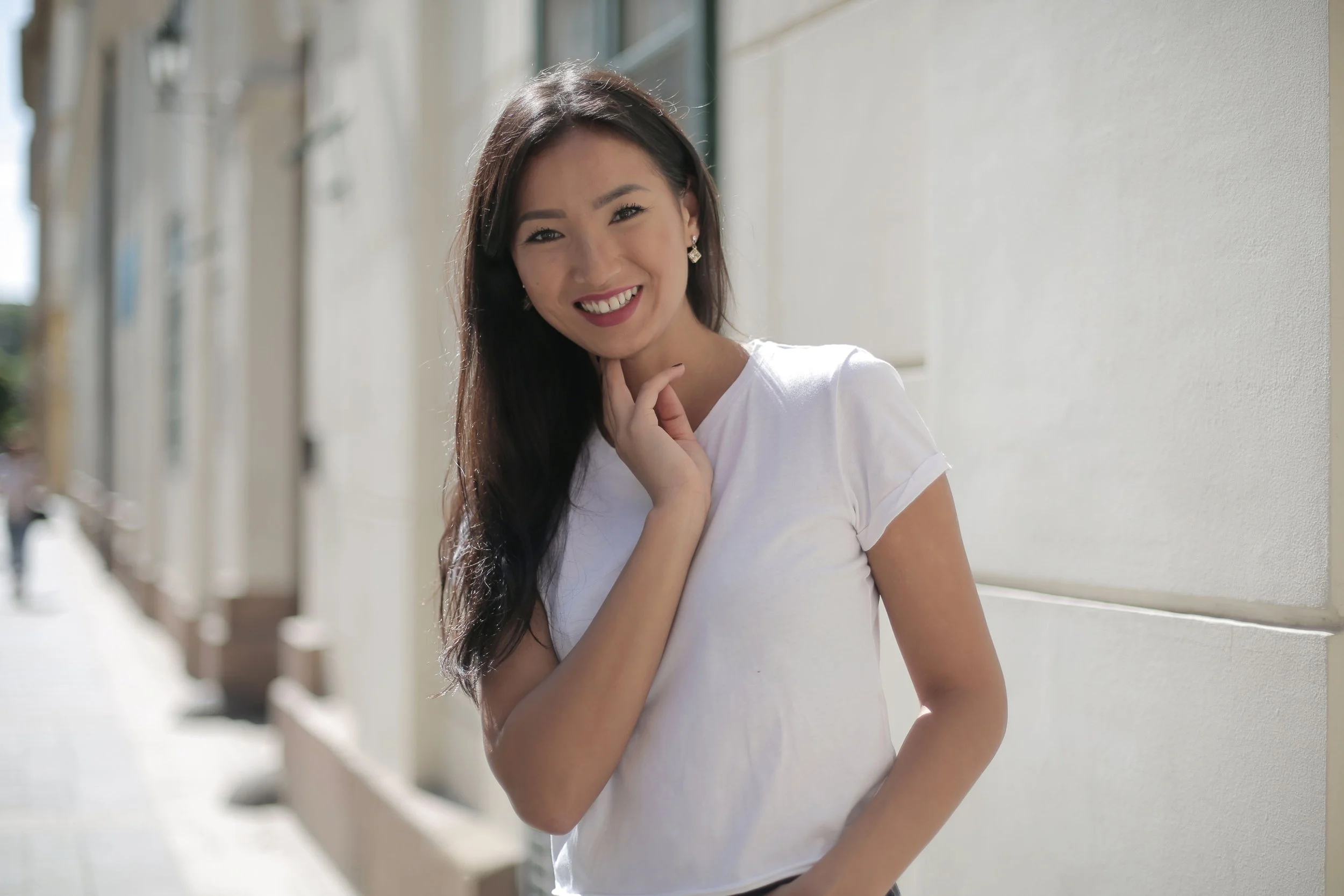 Smiling woman in a white T-shirt standing on a city street