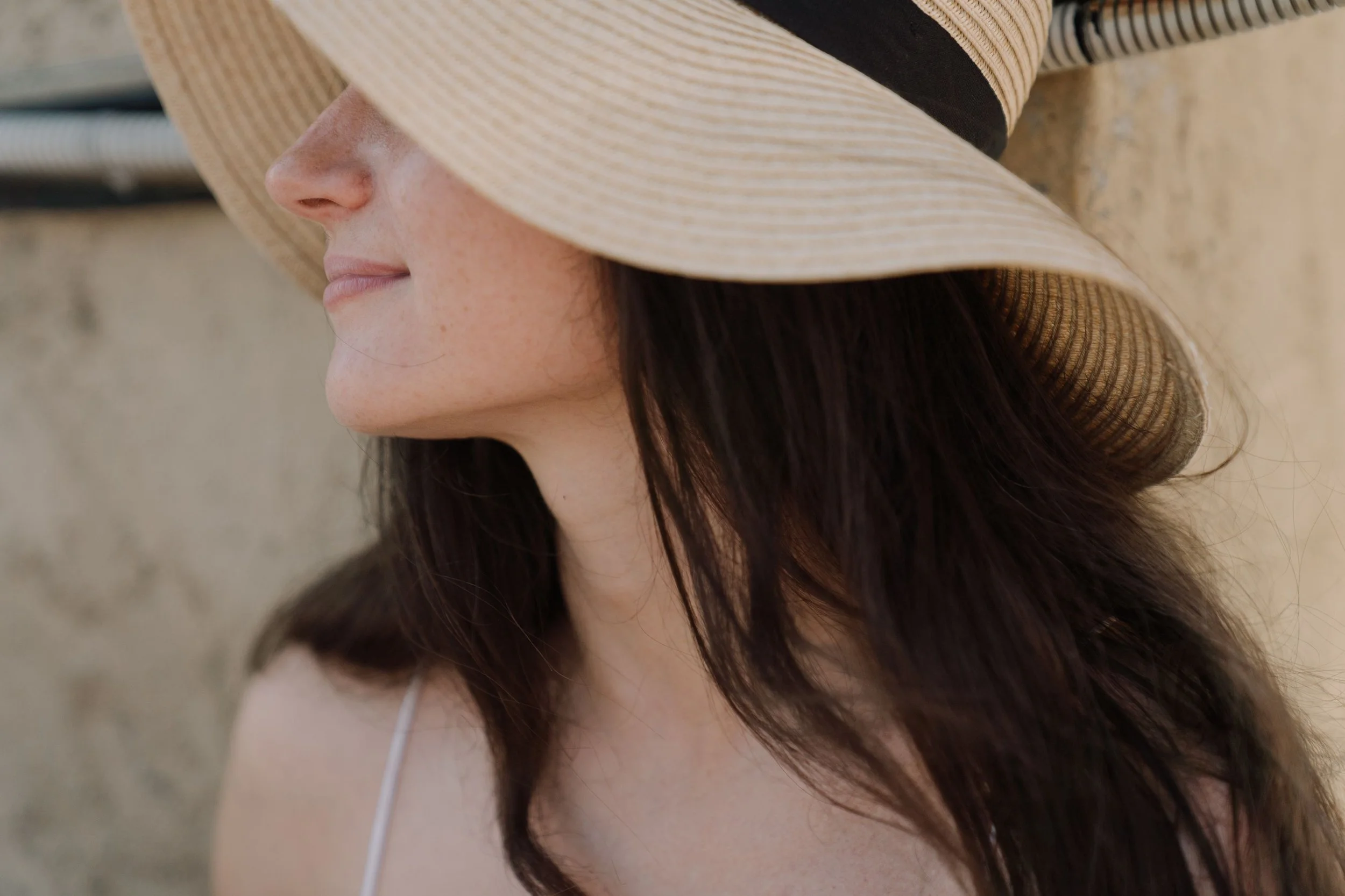 Woman shading her face with a wide-brimmed straw hat