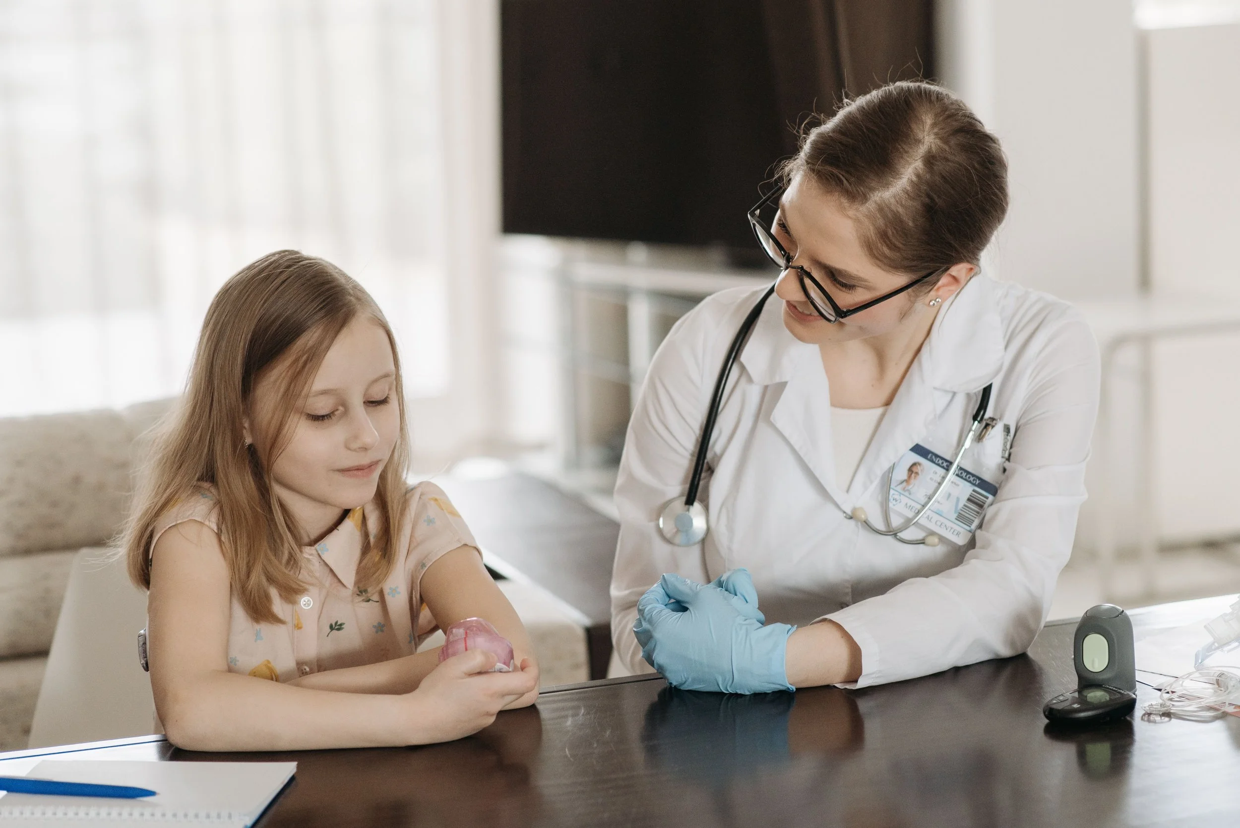Doctor in a white coat talking with a young girl at a table