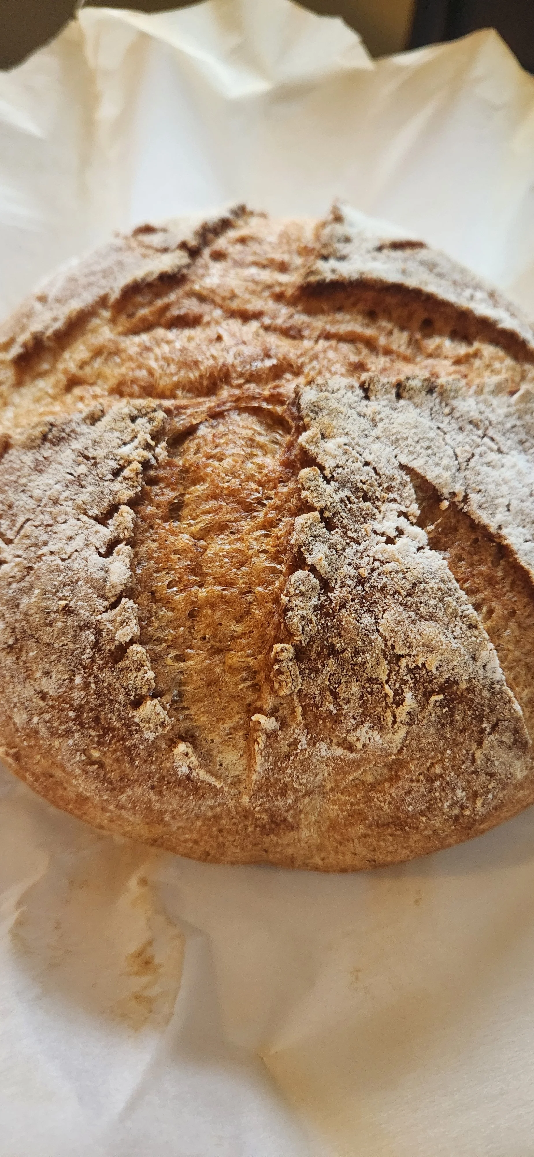 Artisan gluten-free sourdough loaf with a golden, crispy crust and intricate scoring, baked during a private Ember & Bloom workshop in Gig Harbor.