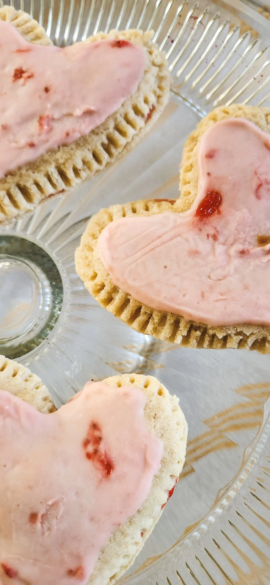 Strawberry gluten-free and vegan pocket pastries in heart shape with a strawberry glaze and crimped crust.