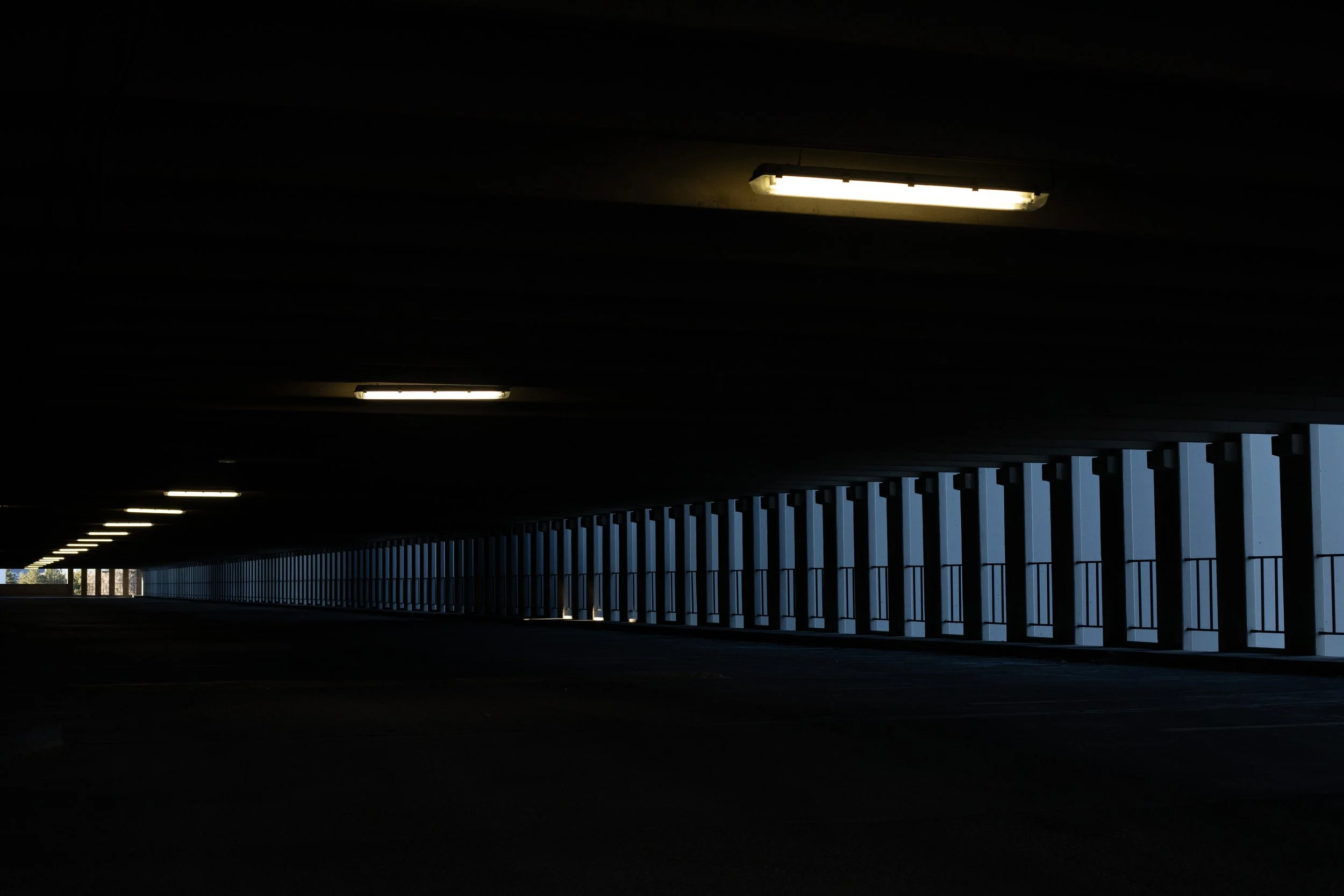 Empty parking deck with receding columns and fluorescent lights, Denver, CO