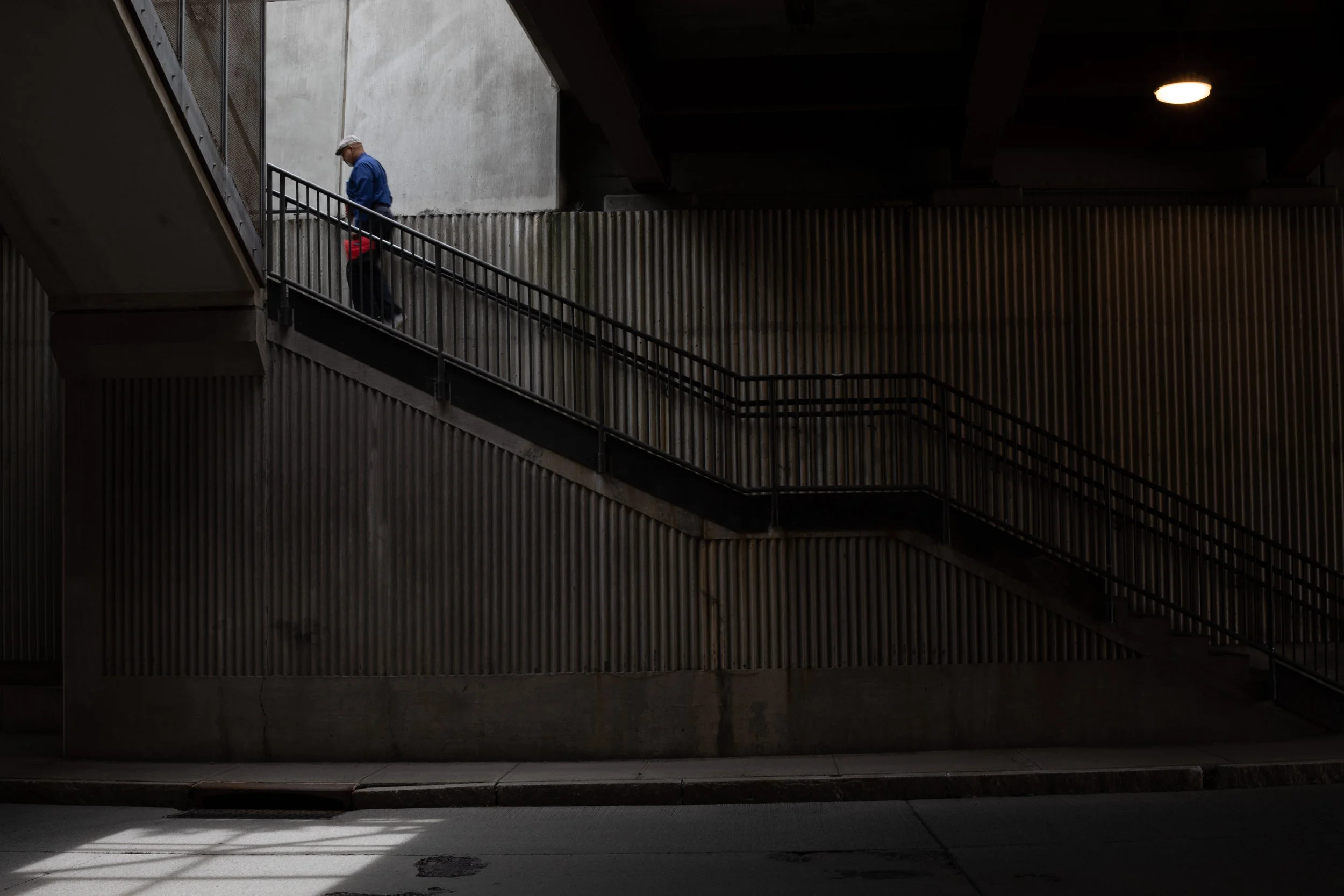 Man descending a metal staircase alongside a corrugated wall, Albany, NY