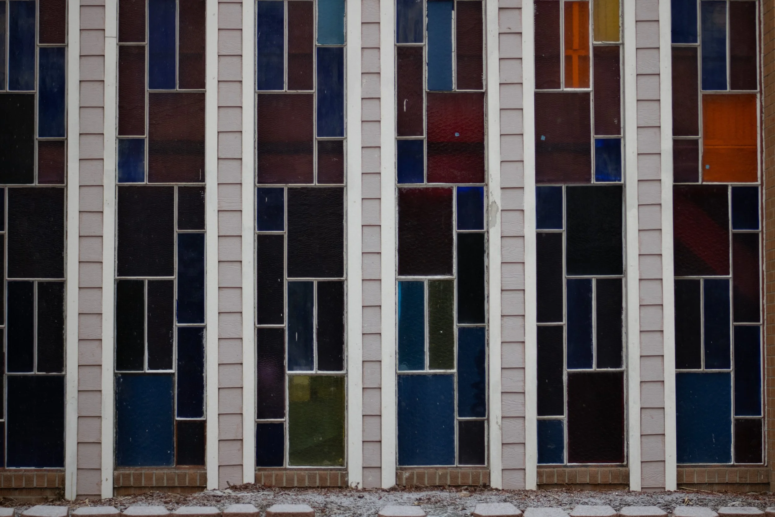 Stained glass panels in blue, red, and amber set in white vertical frames, St. Anthony of Padua Catholic Church, Denver, CO