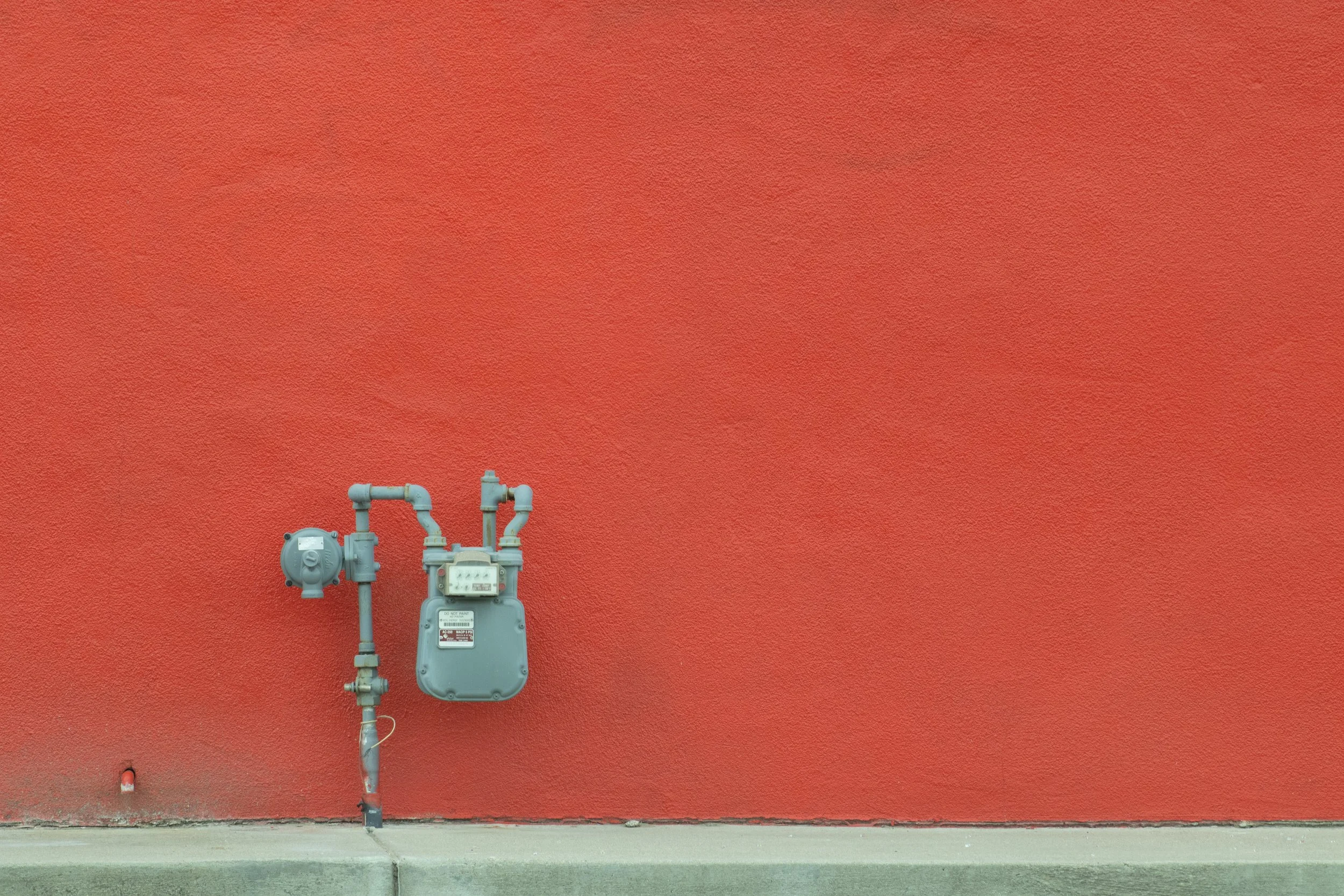Grey gas meter mounted on red stucco wall, Denver, CO