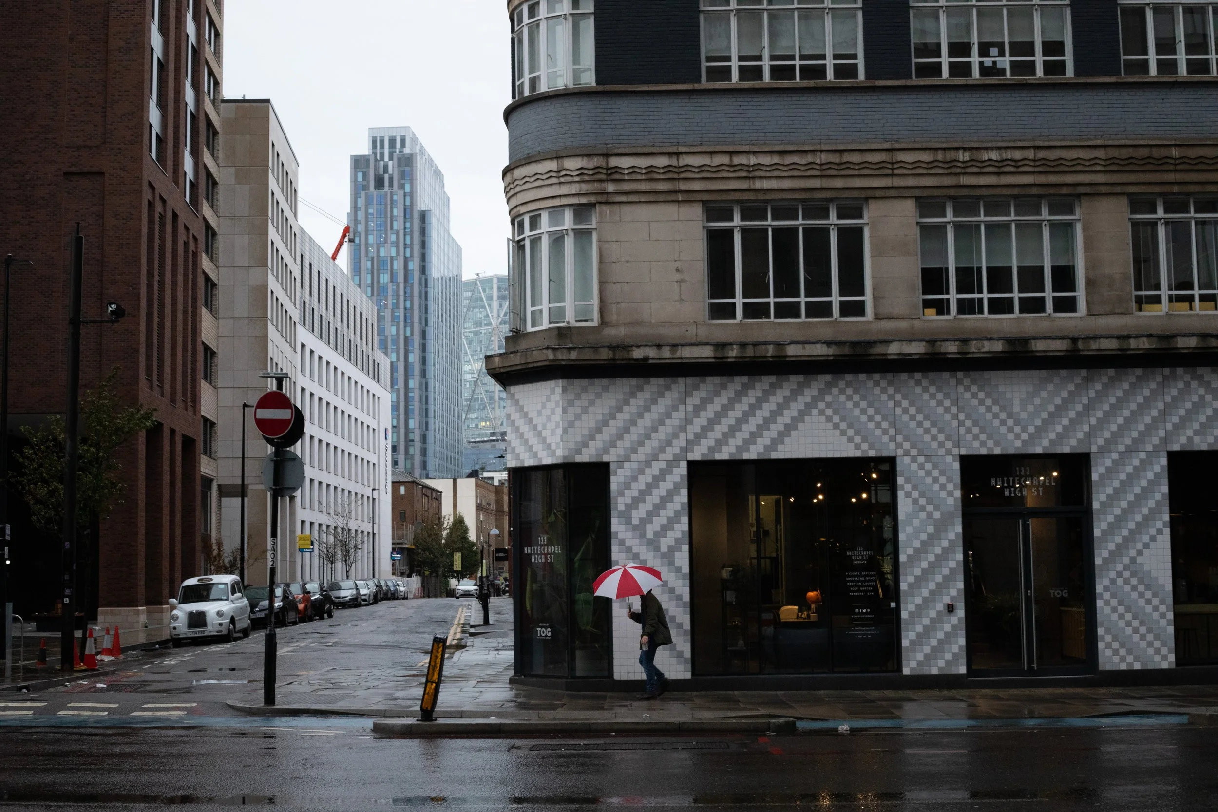 Red umbrella, wet pavement, Art Deco corner, London, UK