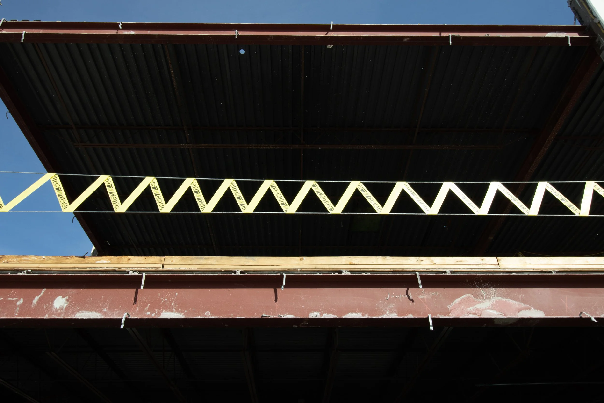 Yellow caution tape strung in a zigzag below corrugated overhand, Grand Junction, CO