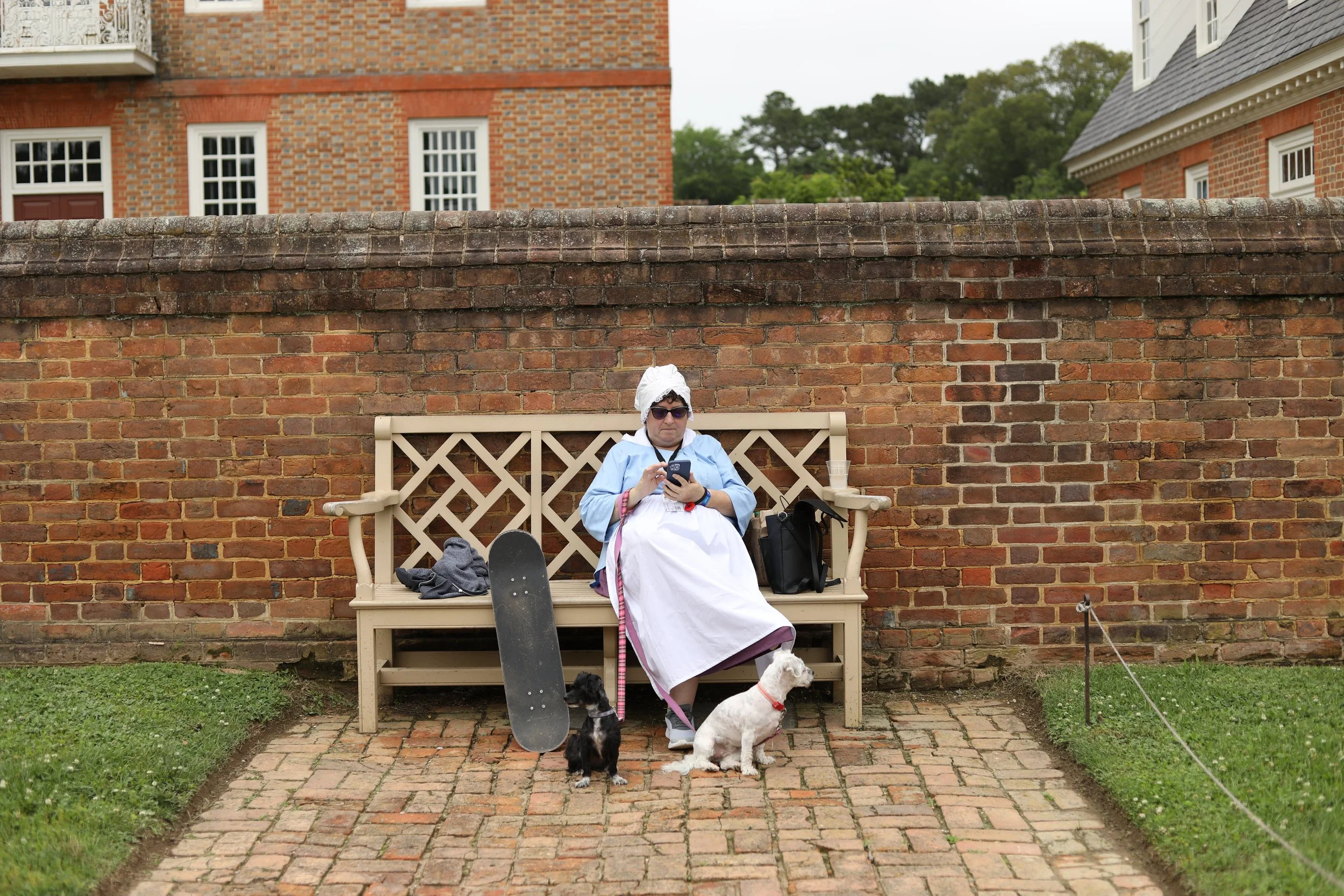 Eighteenth-century costume, sunglasses, skateboard, two dogs, smartphone, Colonial Williamsburg, Virginia