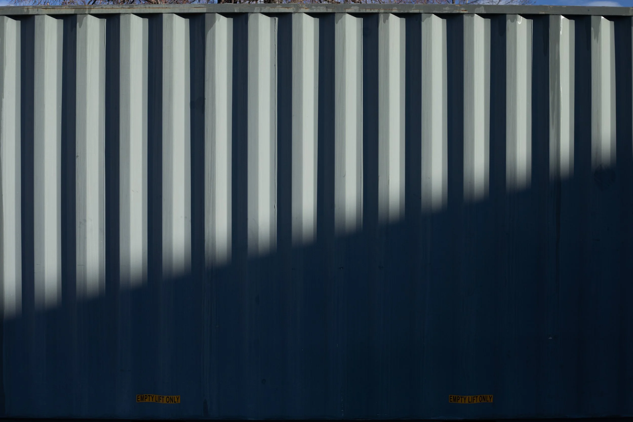 Diagonal shadow across grey corrugated metal, Denver, CO
