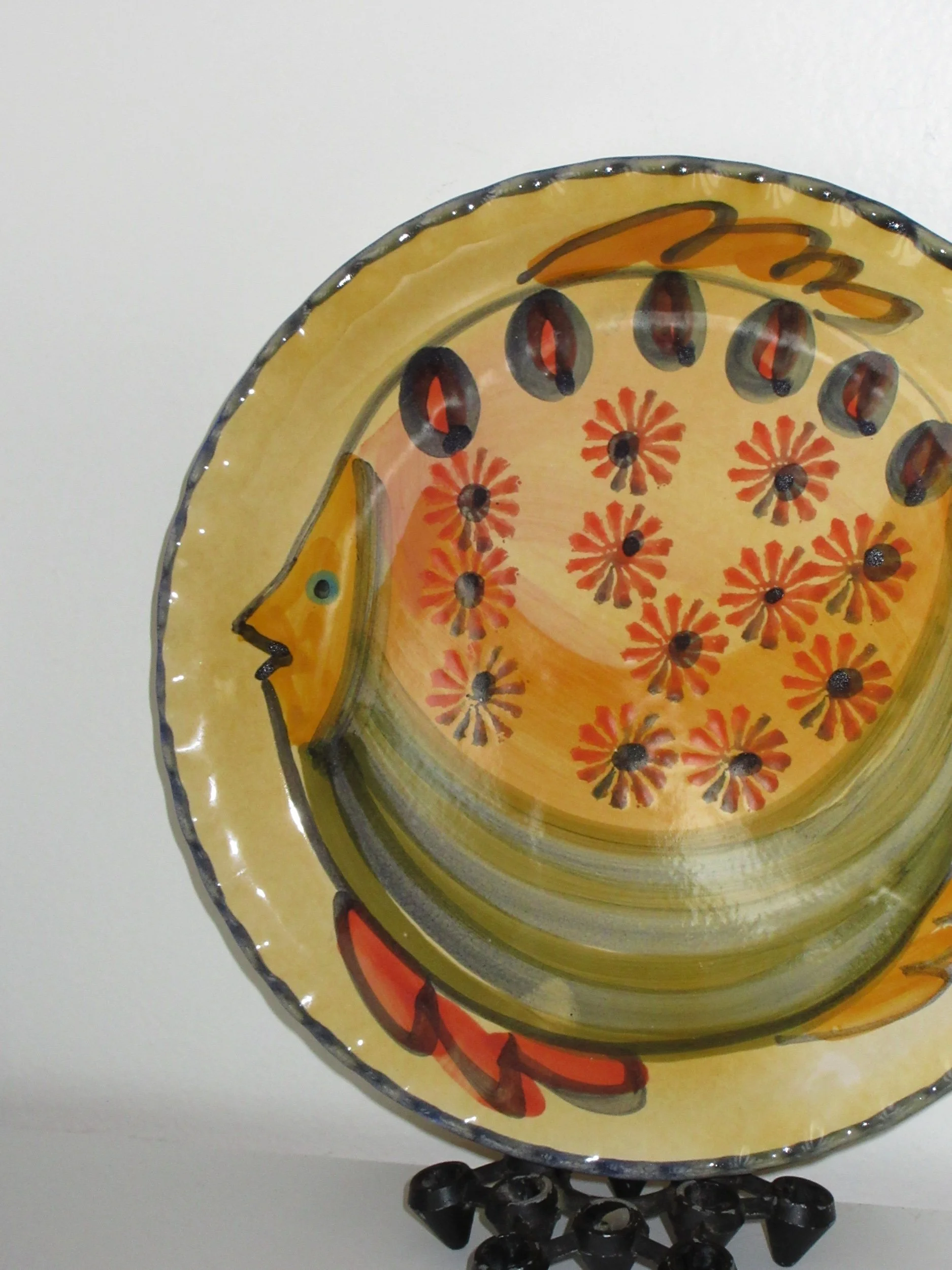 Decorative glass bowl with painted orange and red fish and floral patterns, placed on a stand.